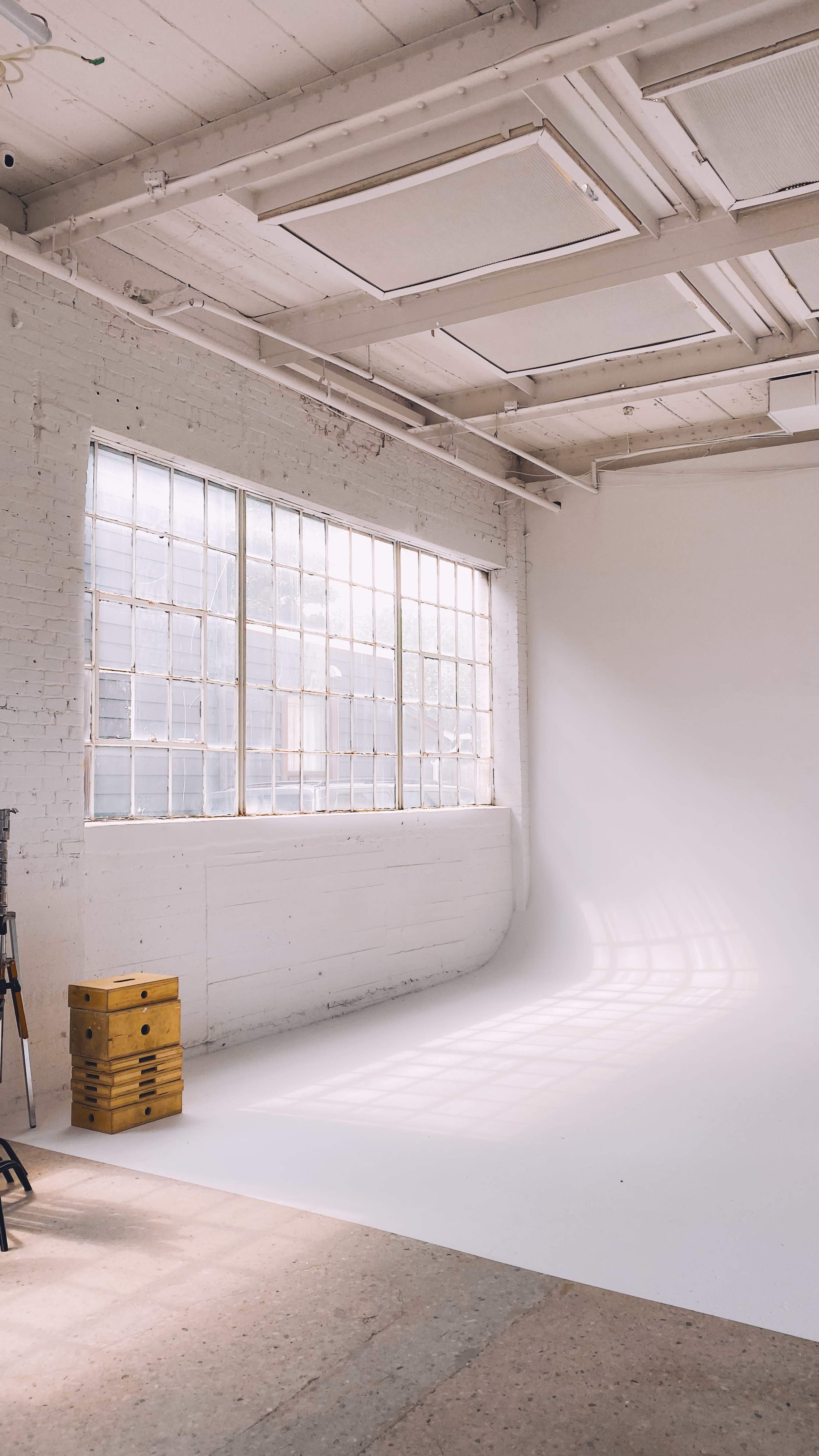 A spacious, well-lit studio with large windows and a white backdrop.