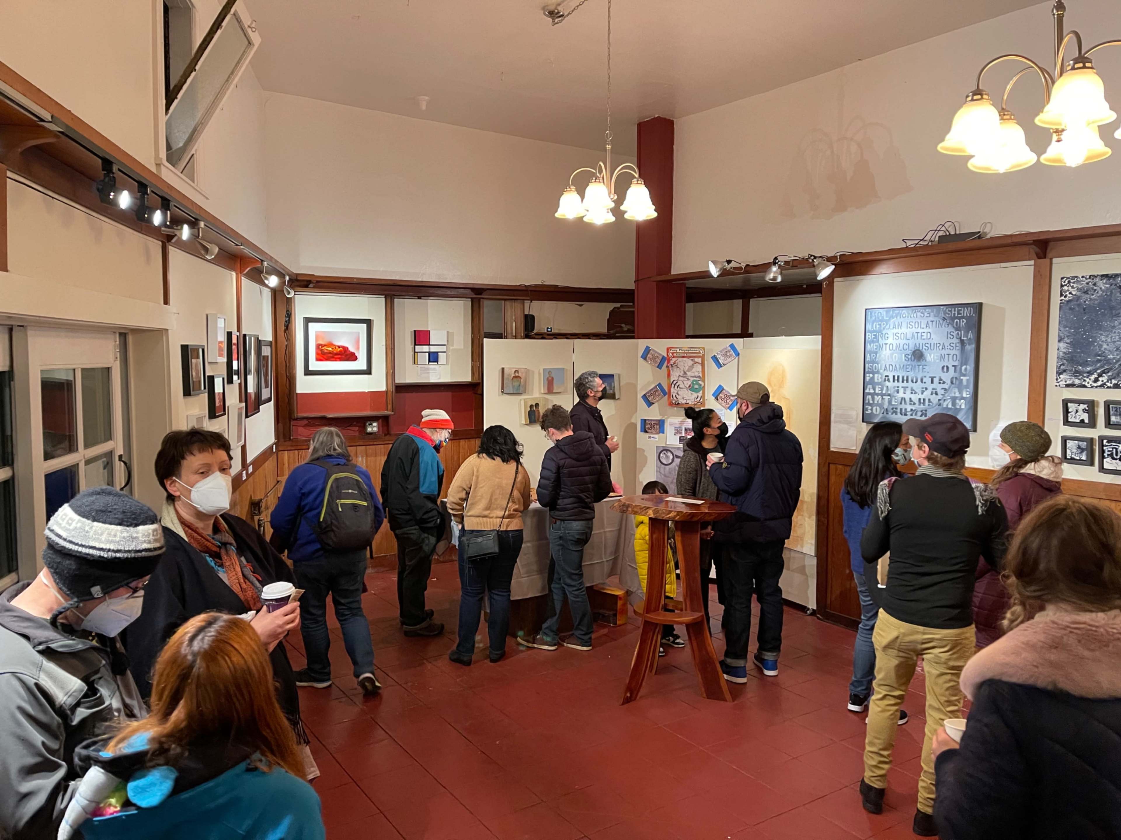 A group of people gathers in an art gallery, viewing various artworks displayed on the walls.