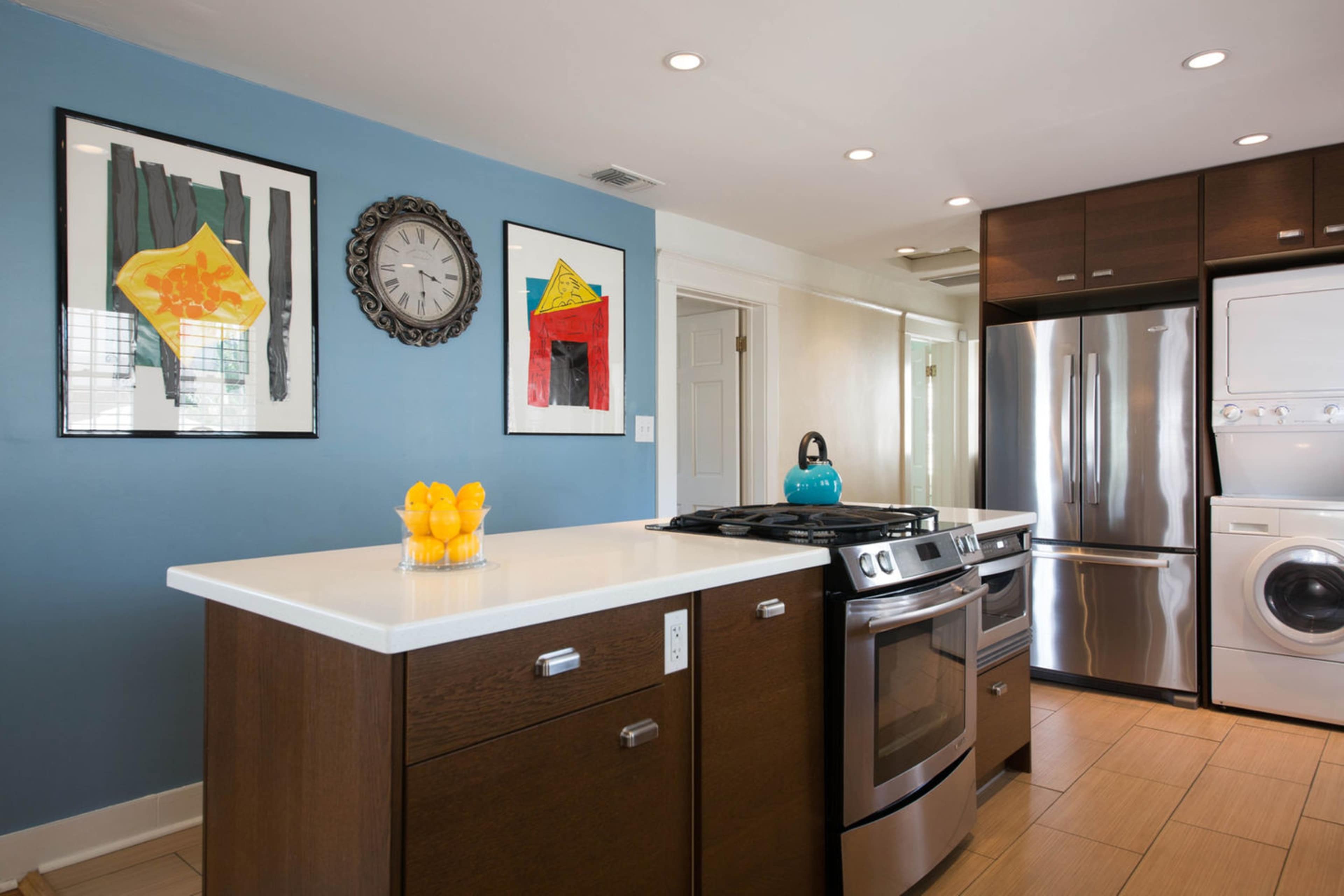 A modern kitchen features a gas stove, stainless steel appliances, and a prominent island with a bowl of lemons.