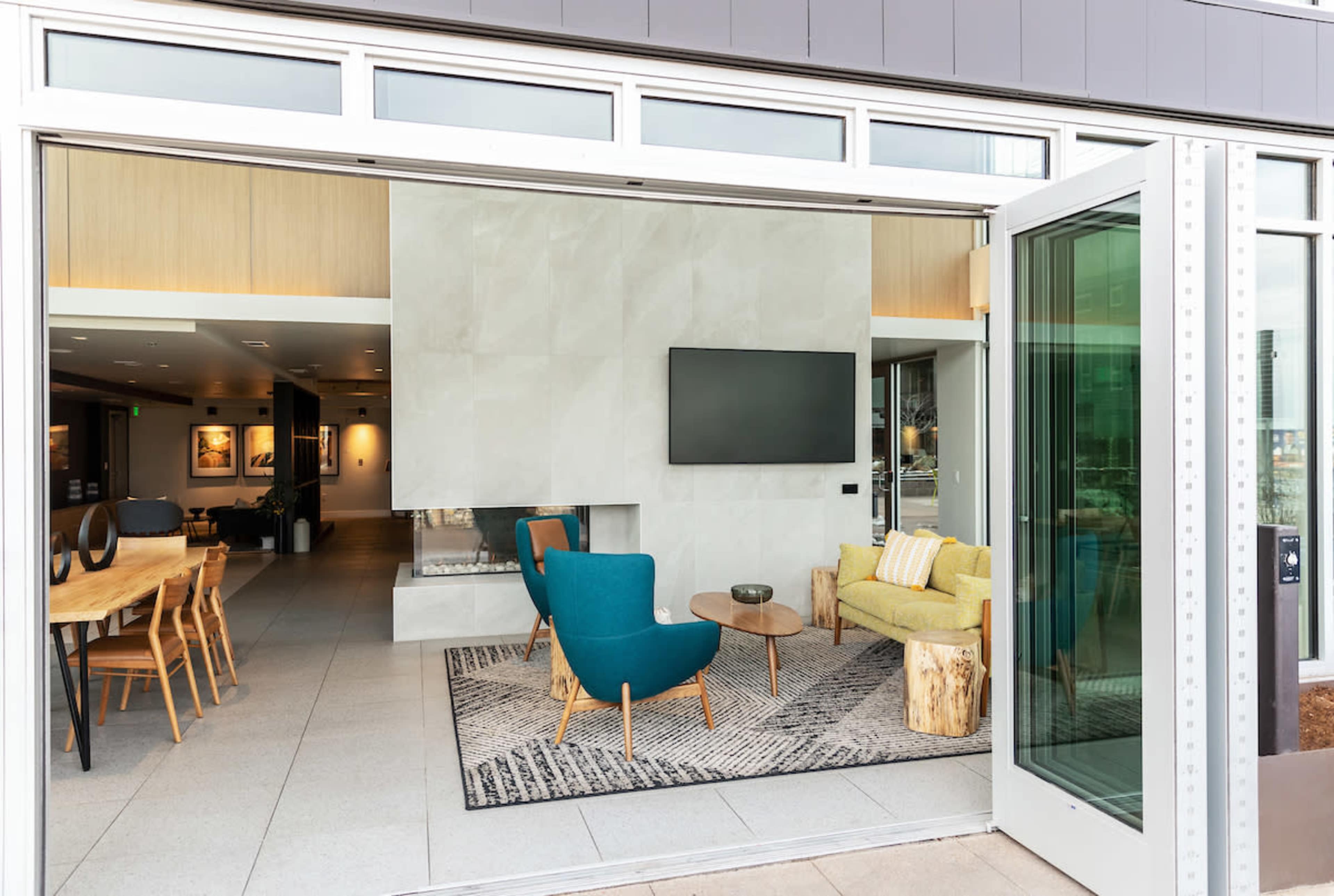 The image features a modern indoor space with a seating area, a dining table, and a large wall-mounted TV.
