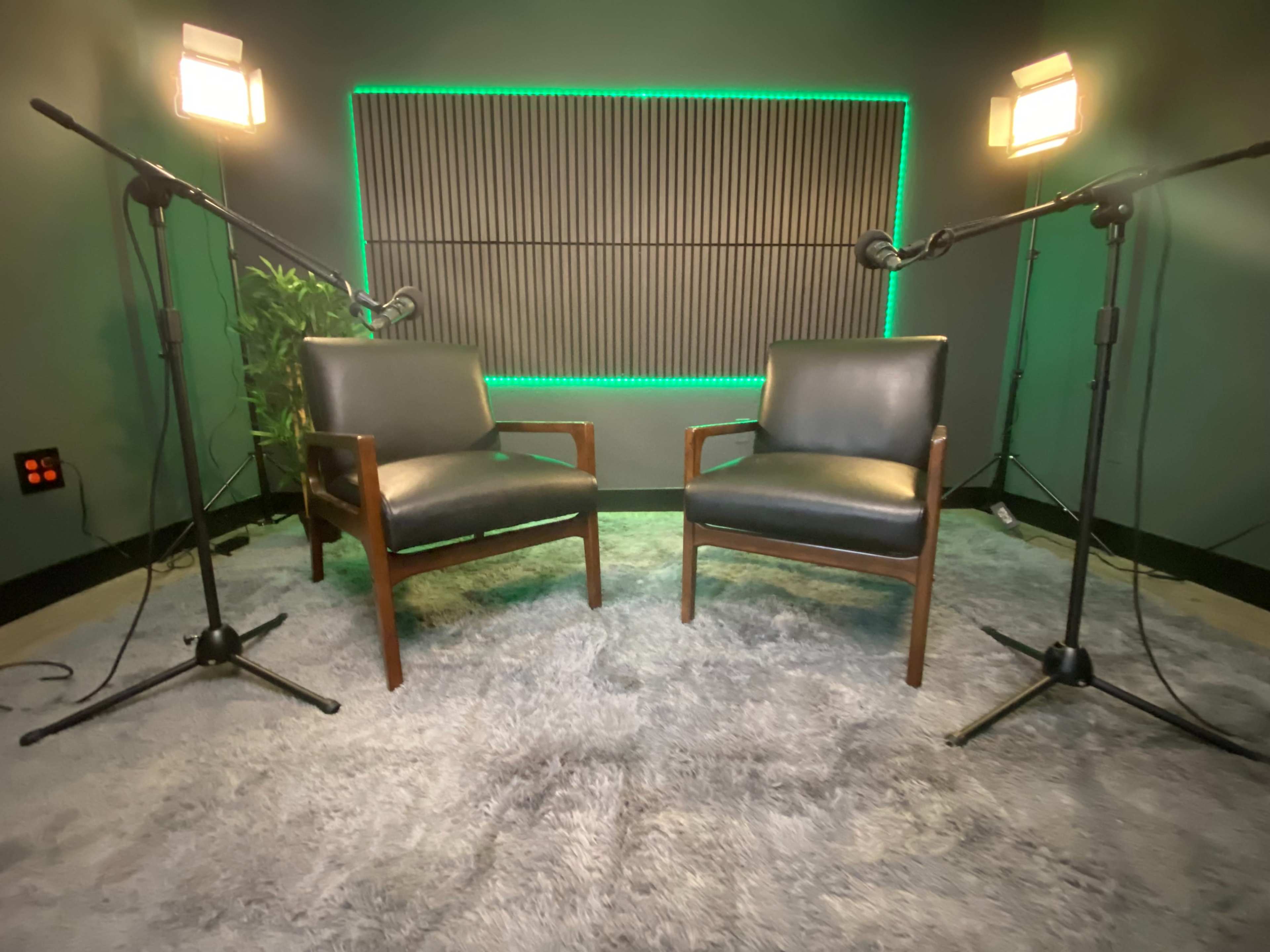 Two wooden chairs positioned facing each other under bright lights in a soundproofed room.