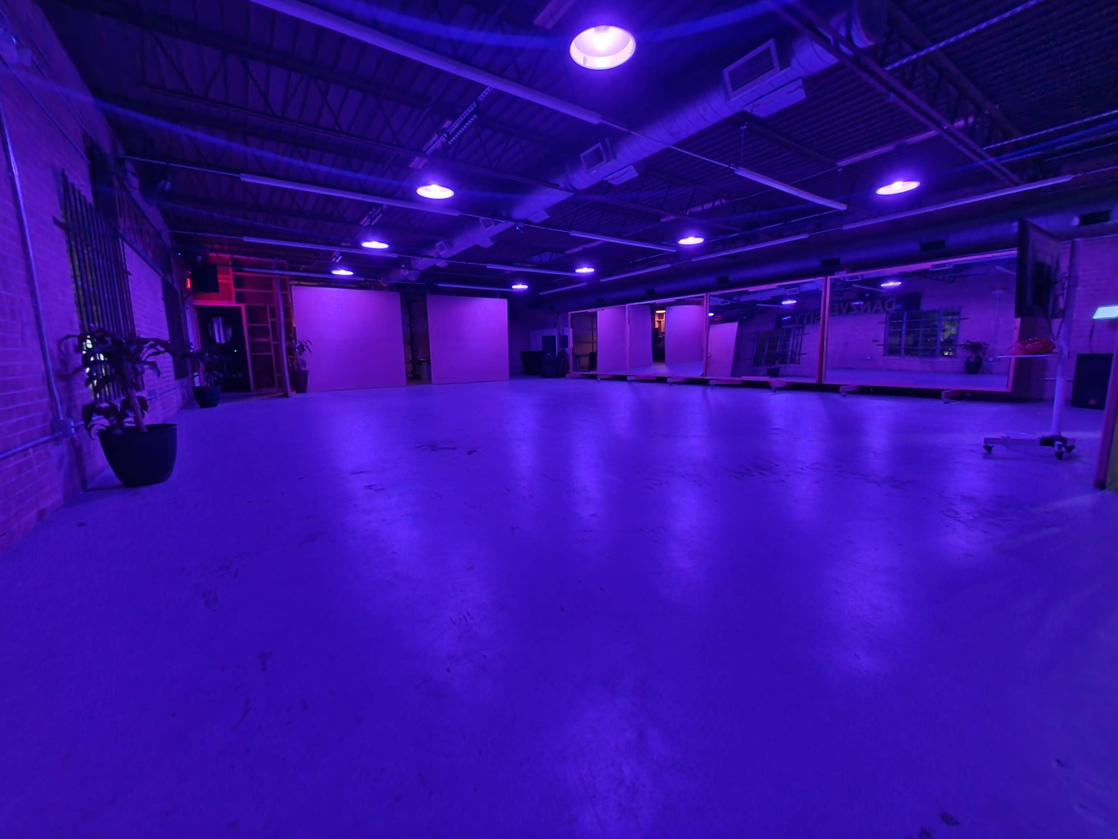 An empty, well-lit room with purple lighting and concrete flooring.