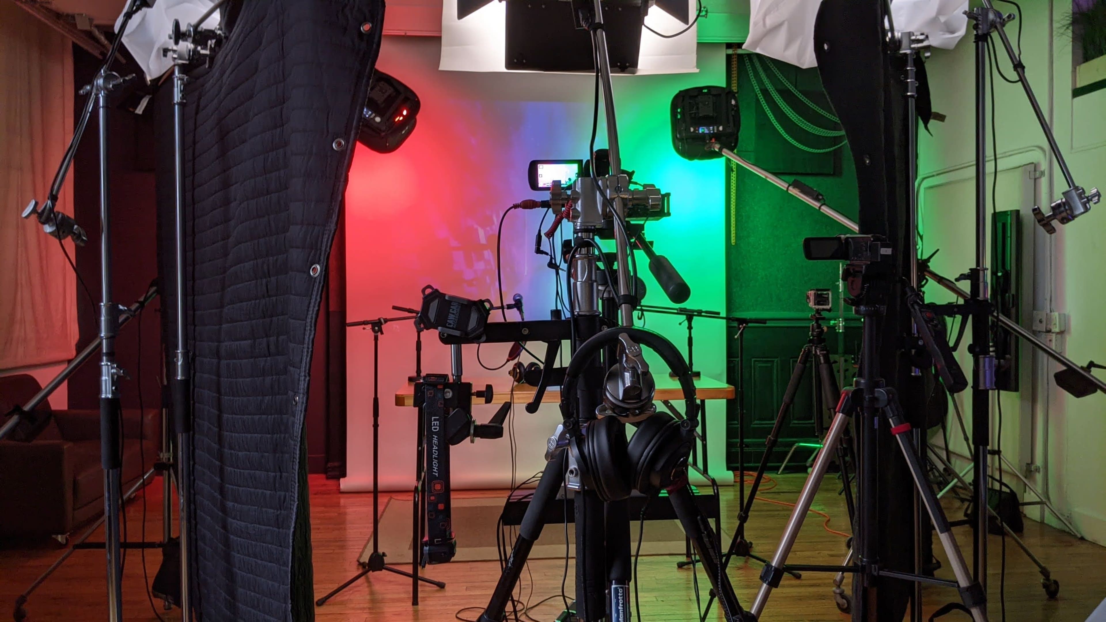 A photography or video recording setup with multiple cameras, lights, and audio equipment arranged on tripods in a studio space.