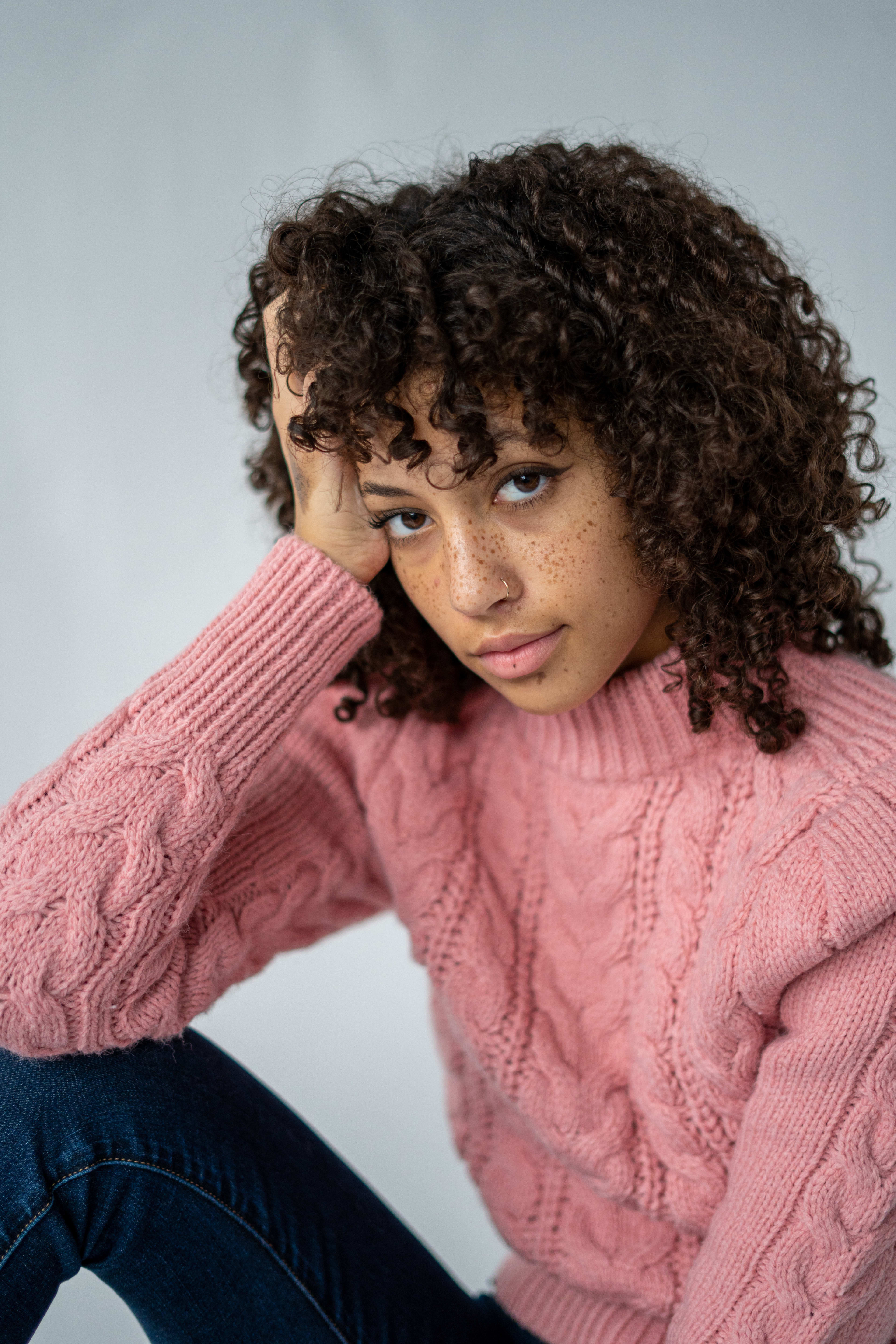 A portrait of a woman in pink with curly hair.