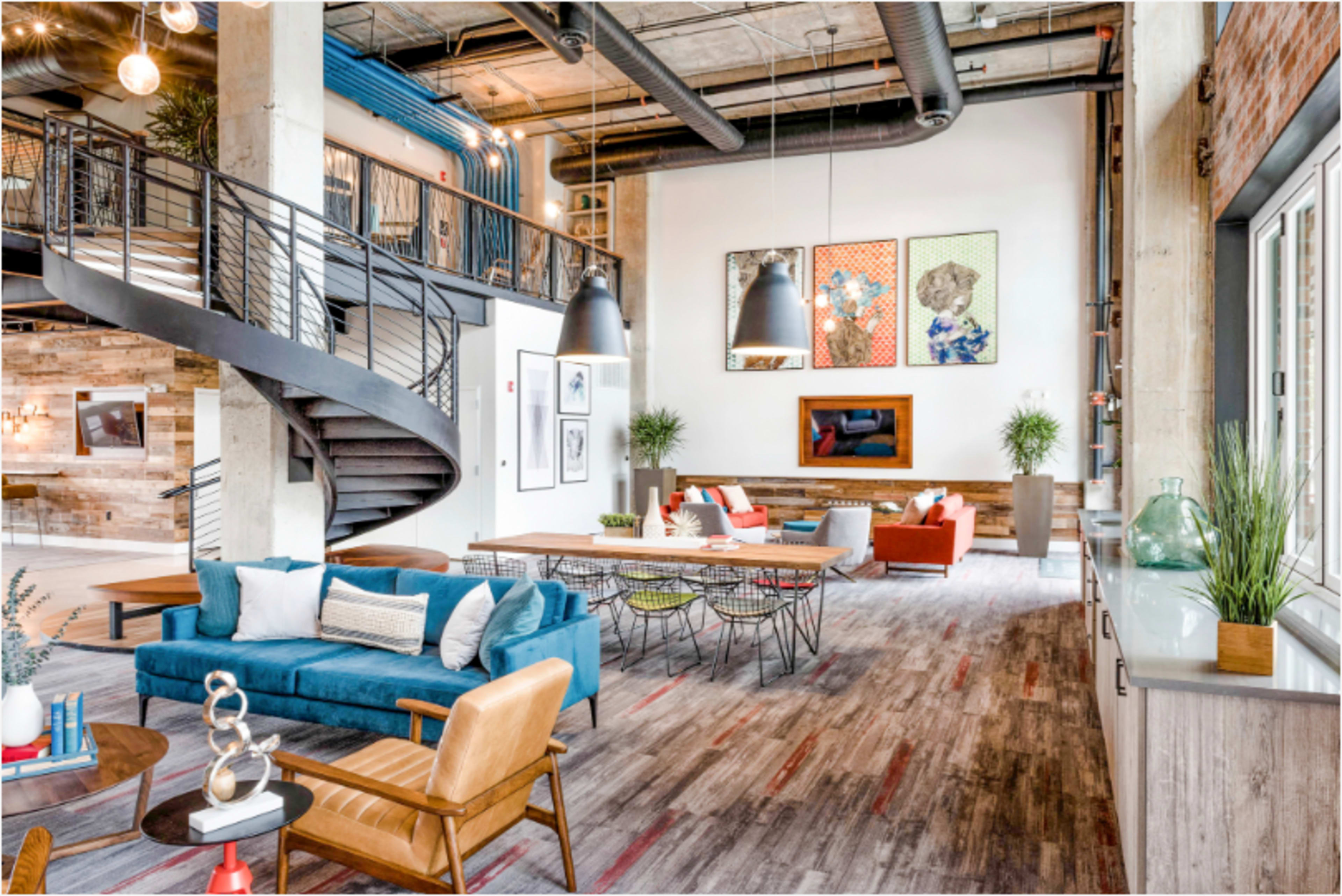 A spacious, modern interior features a staircase, comfortable seating areas, and vibrant artwork on the walls.