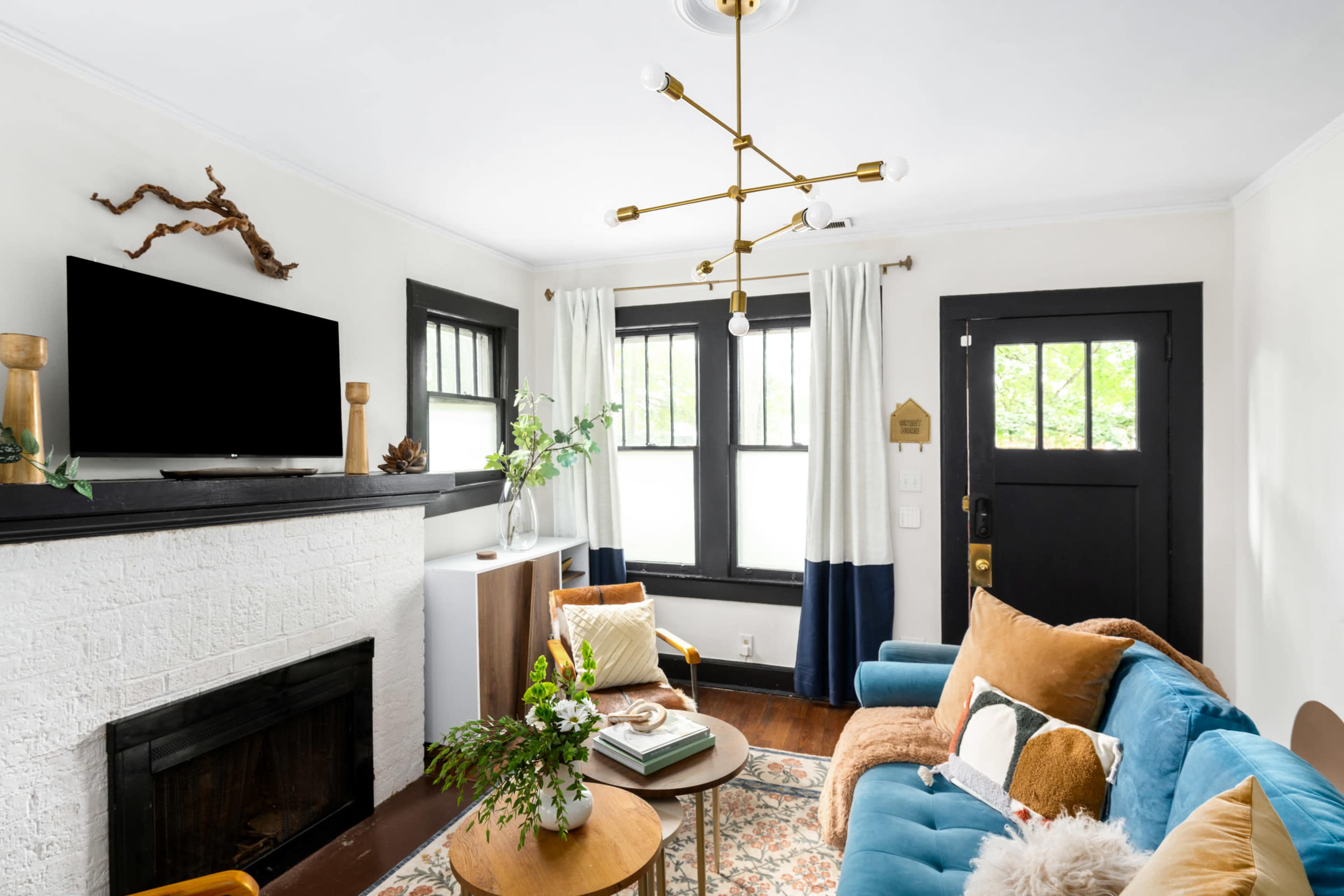 The image shows a cozy living room with a blue sofa, a wooden coffee table, a decorative fireplace, and a television mounted on the wall.