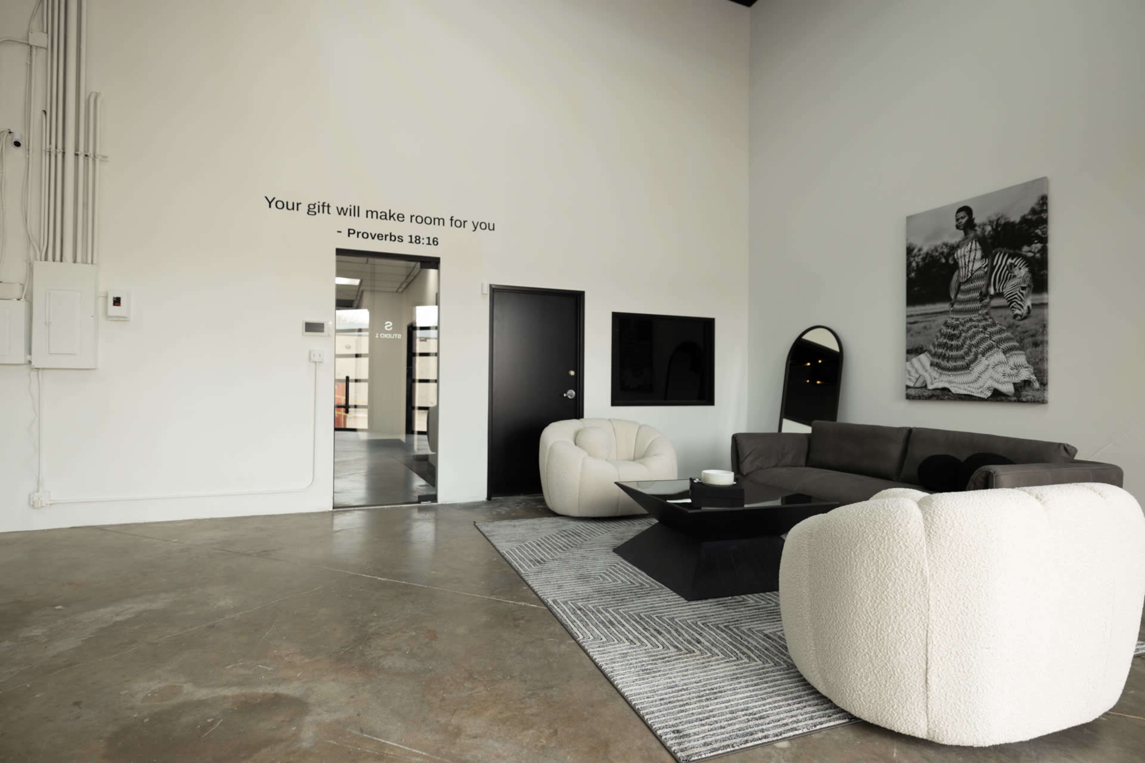 A spacious, modern living area features a gray sectional sofa, a round coffee table, and an inspirational quote displayed on the wall.