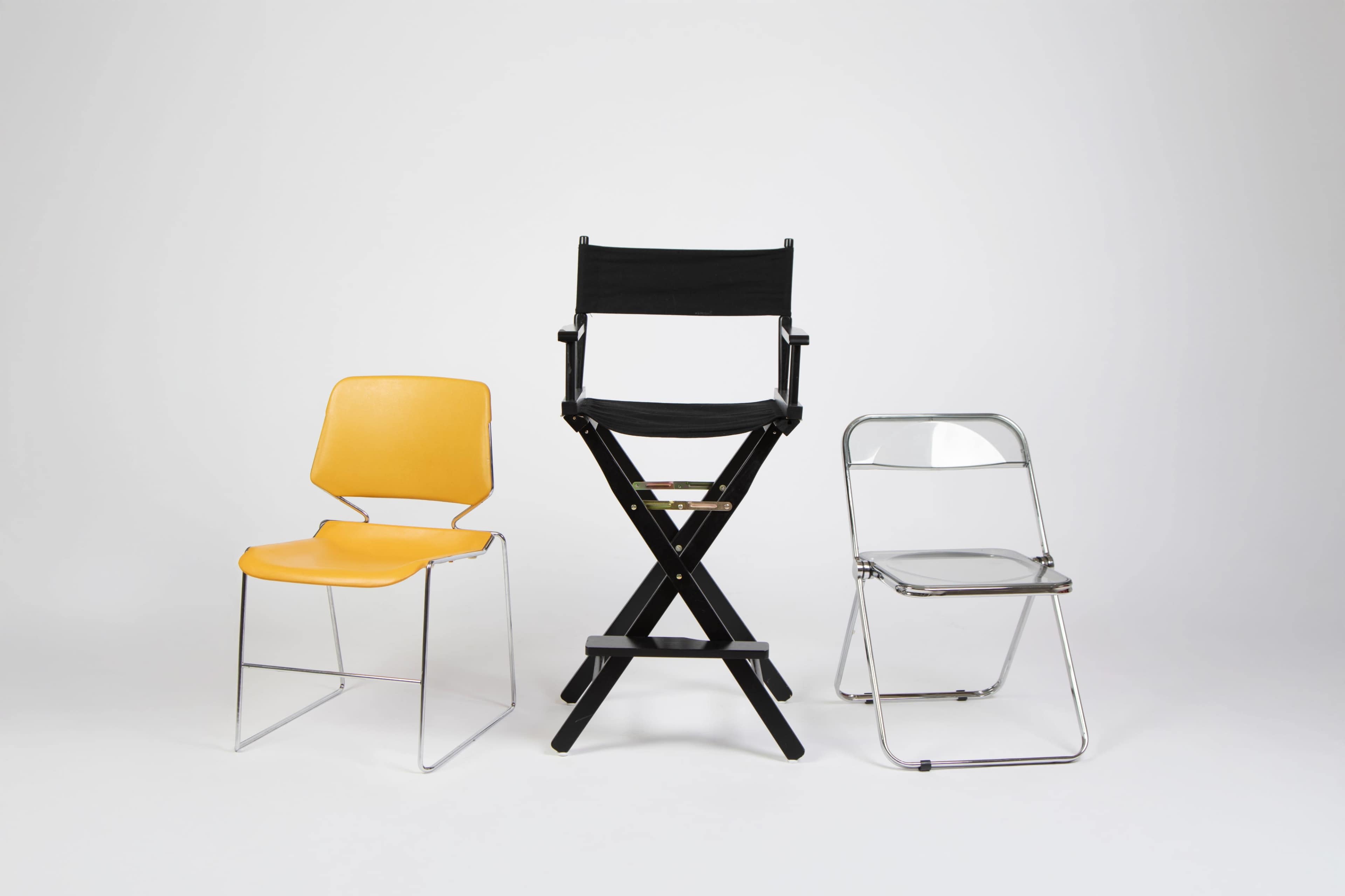 The image features three distinct chairs arranged in a row: a yellow plastic chair, a black director's chair, and a metallic folding chair.