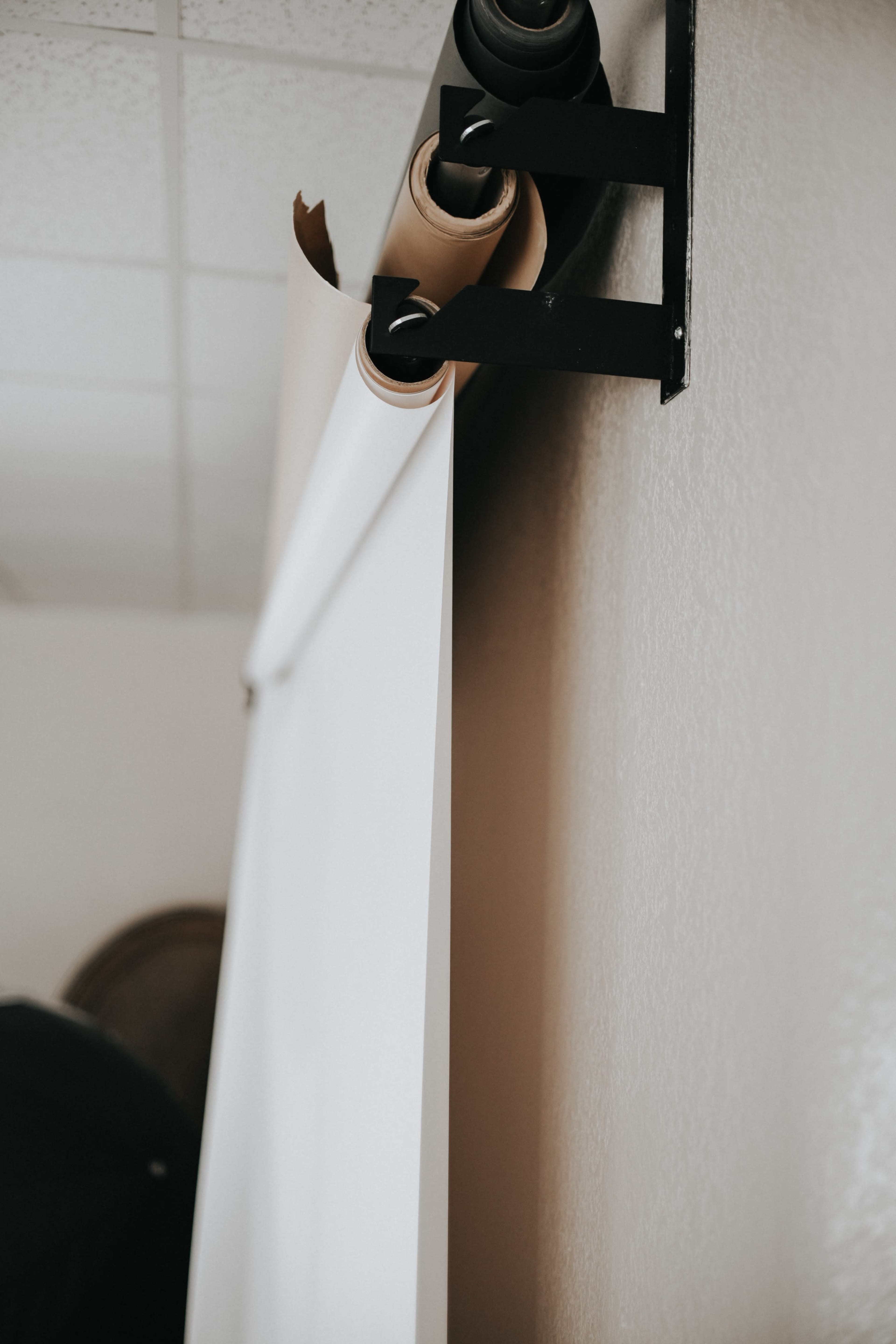 A roll of blank paper hangs from a wall-mounted holder in a room.