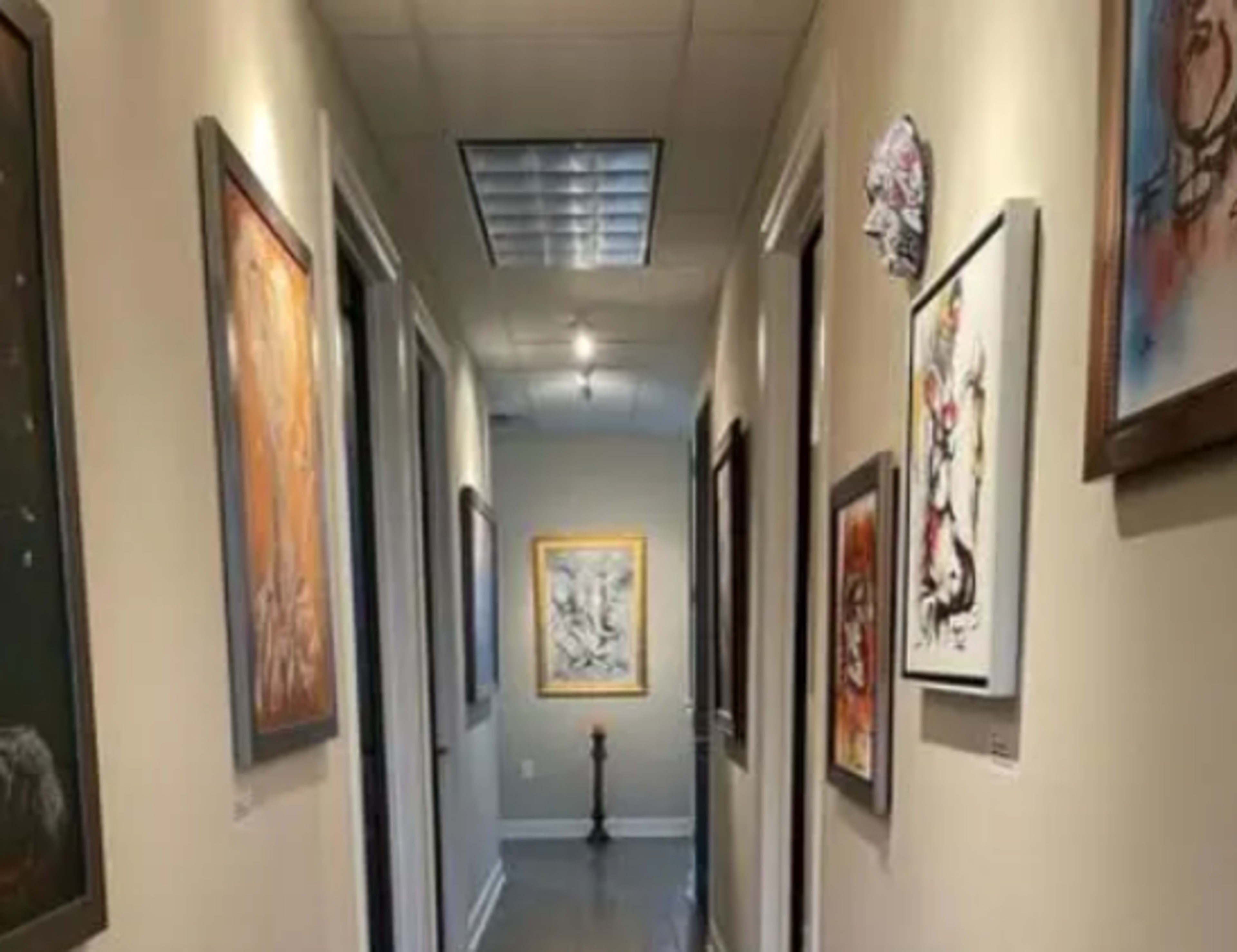 A corridor features several framed artworks on the walls alongside closed doors.
