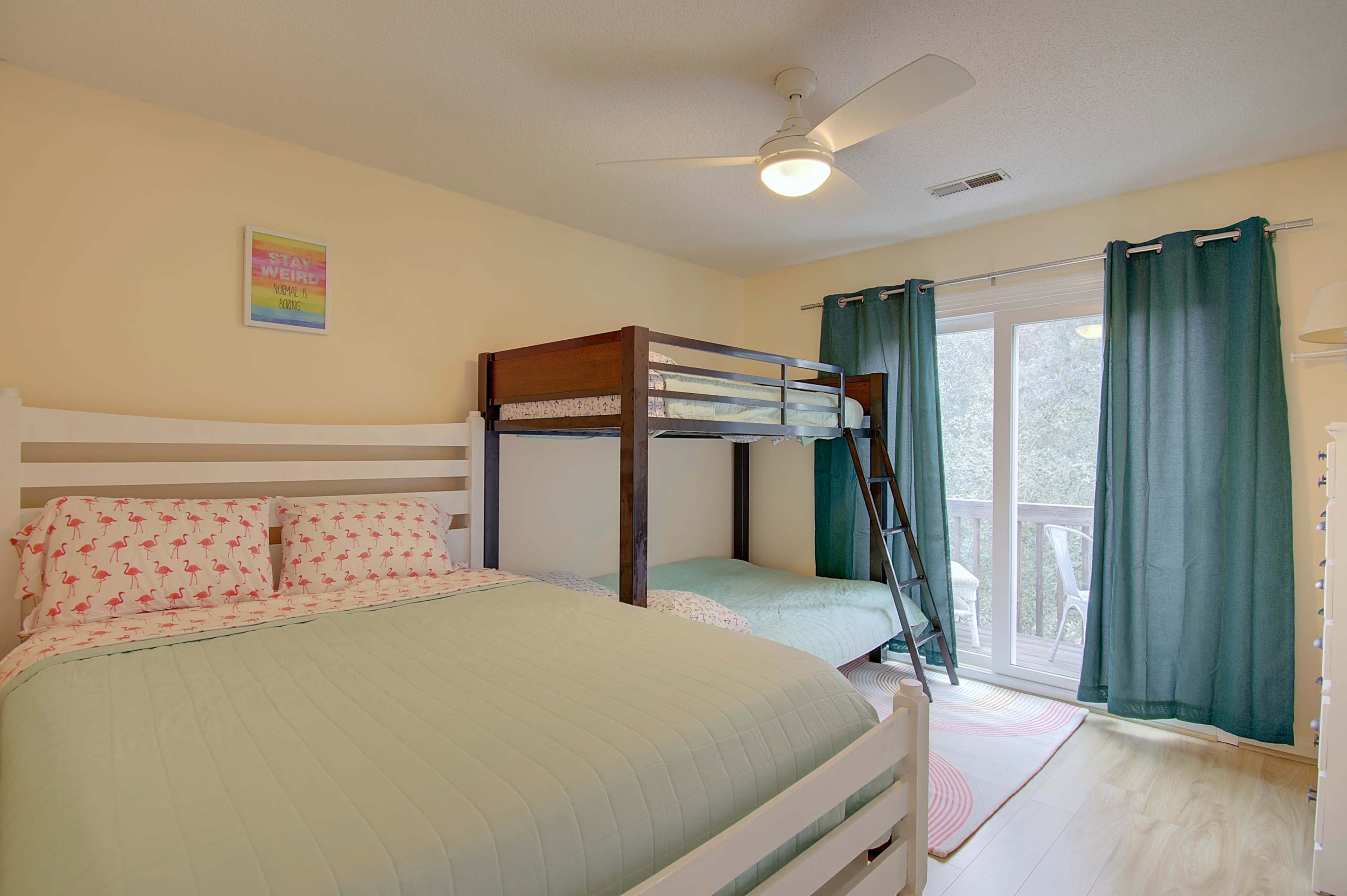 A bright bedroom features a double bed and a bunk bed, along with a large window covered by teal curtains.