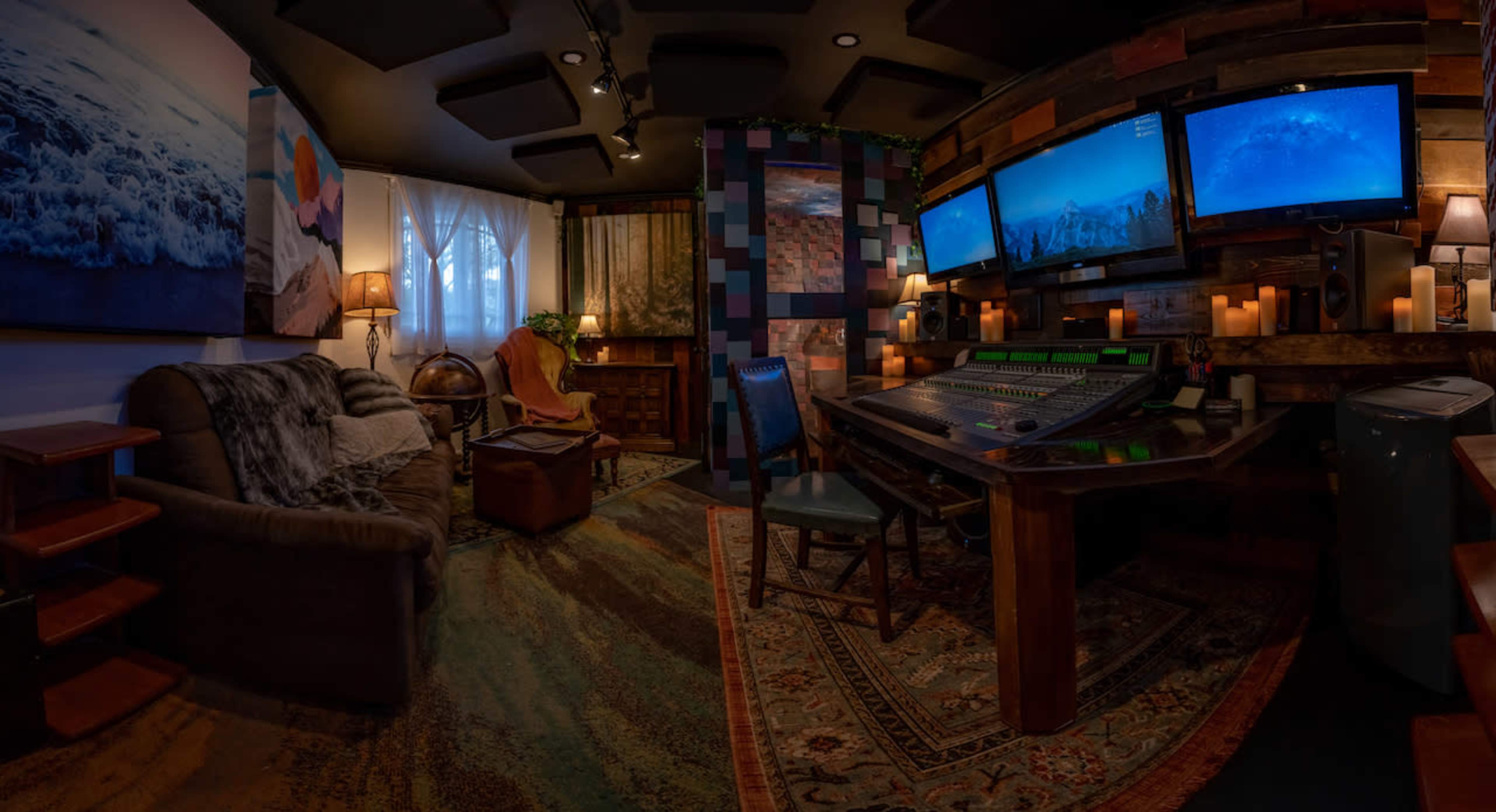 The image shows a cozy audio recording studio with a mixing console, multiple monitors displaying ocean scenes, comfortable seating, and ambient lighting.