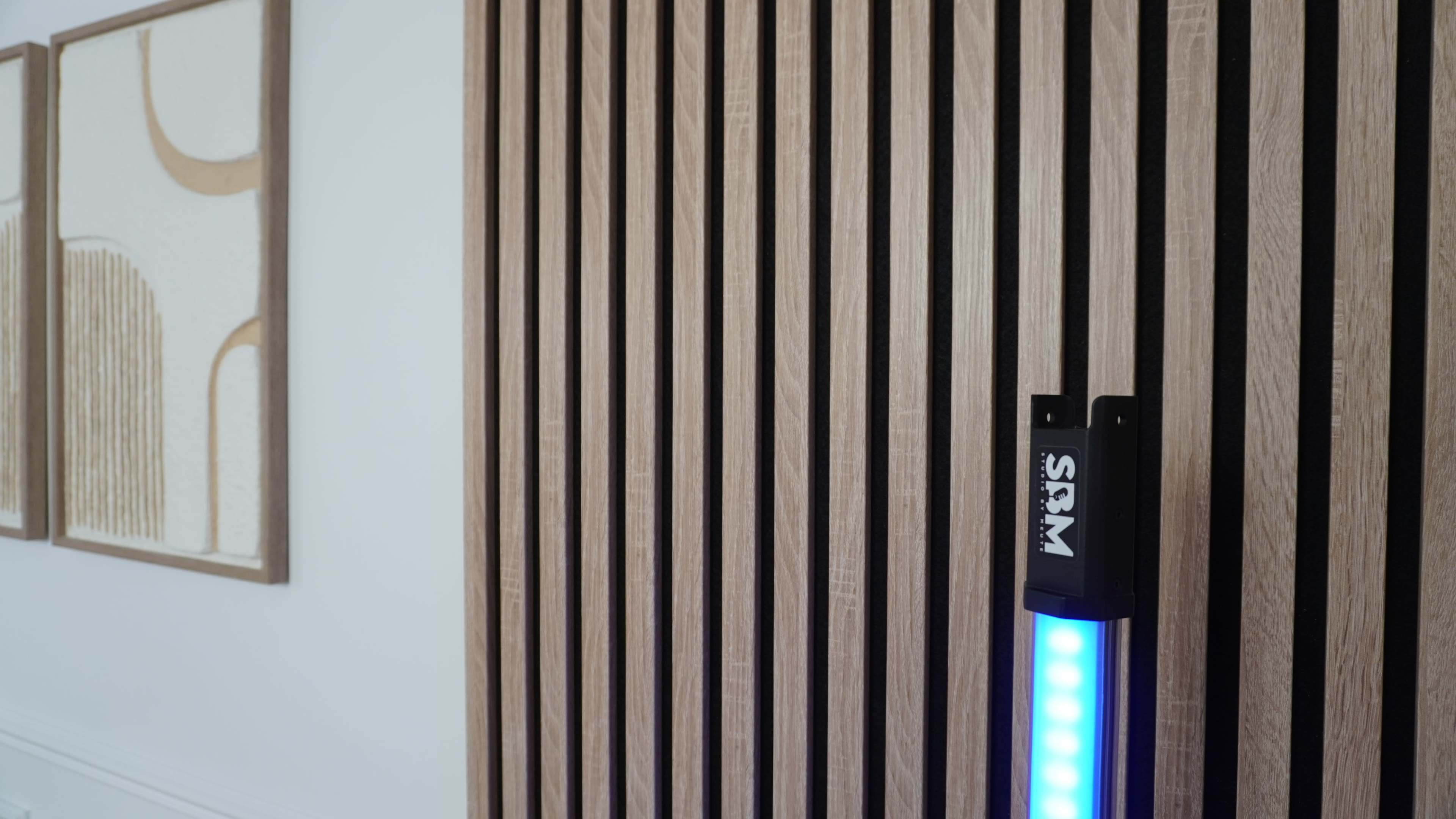 The image shows a wooden wall with vertical slats and a blue-lit device mounted on it.