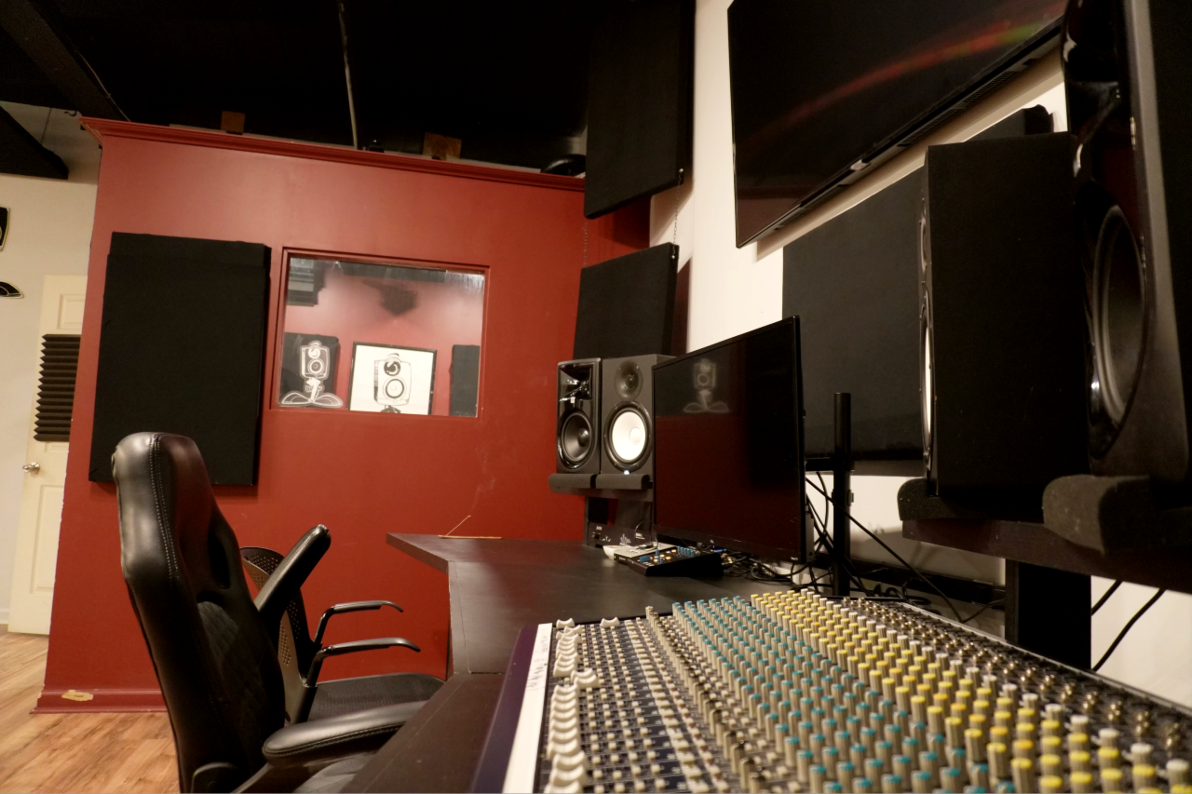 A music studio with a mixing console, multiple speakers, and soundproofed walls.