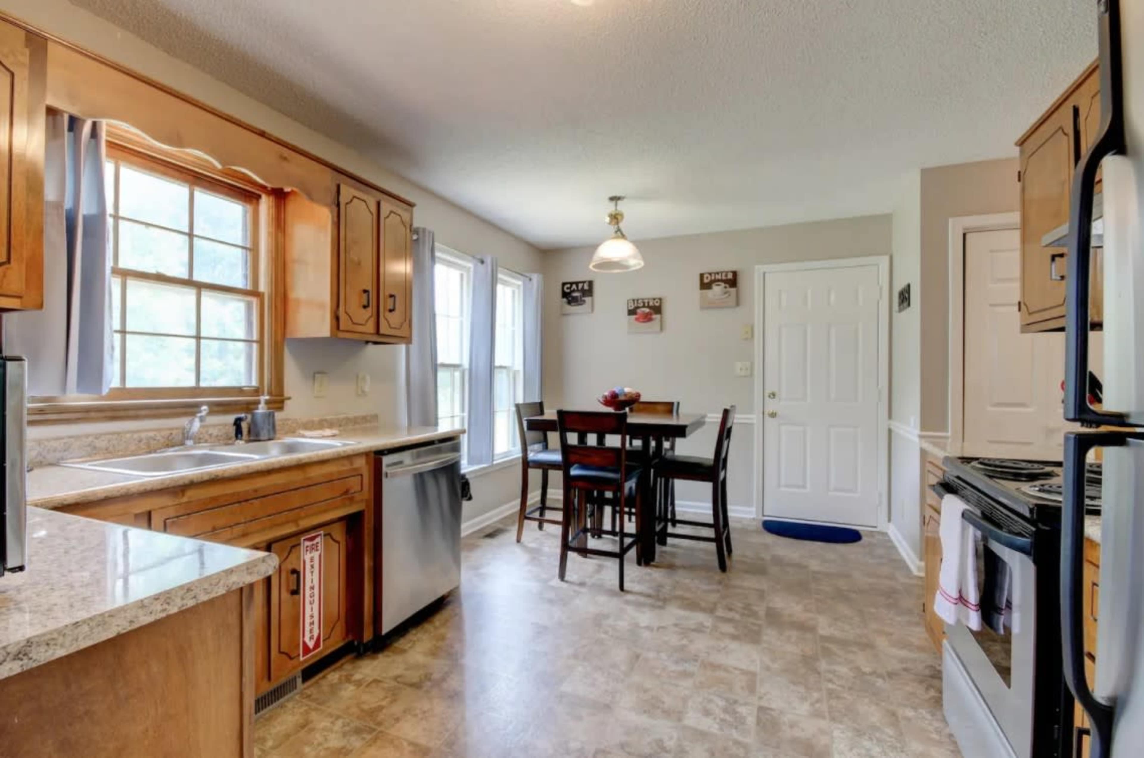 A kitchen features wood cabinets, a granite countertop, a dining table with four chairs, and a window allowing natural light.