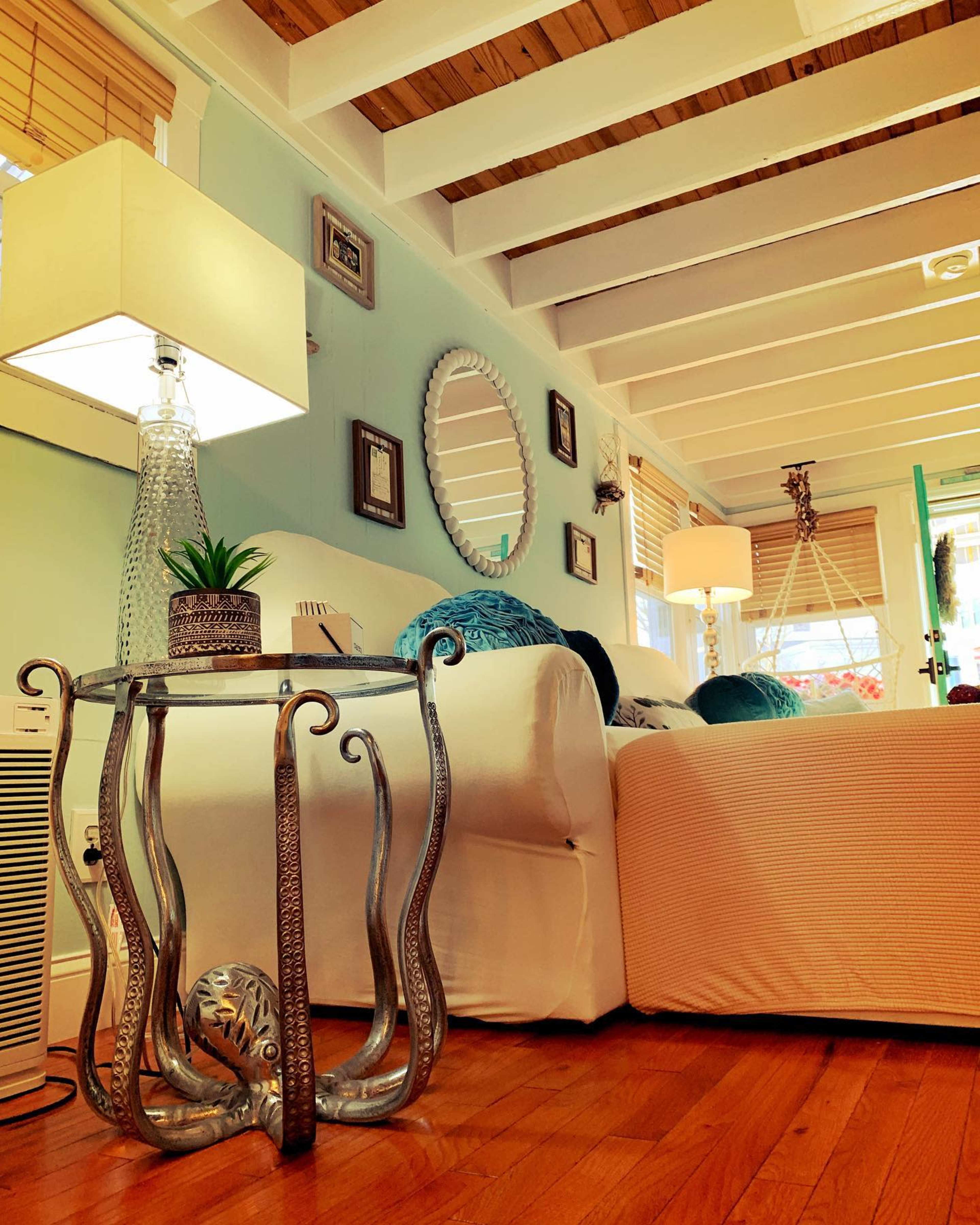 A living room features a modern lamp, a decorative side table with an intricate design, and a cozy sofa with decorative pillows.