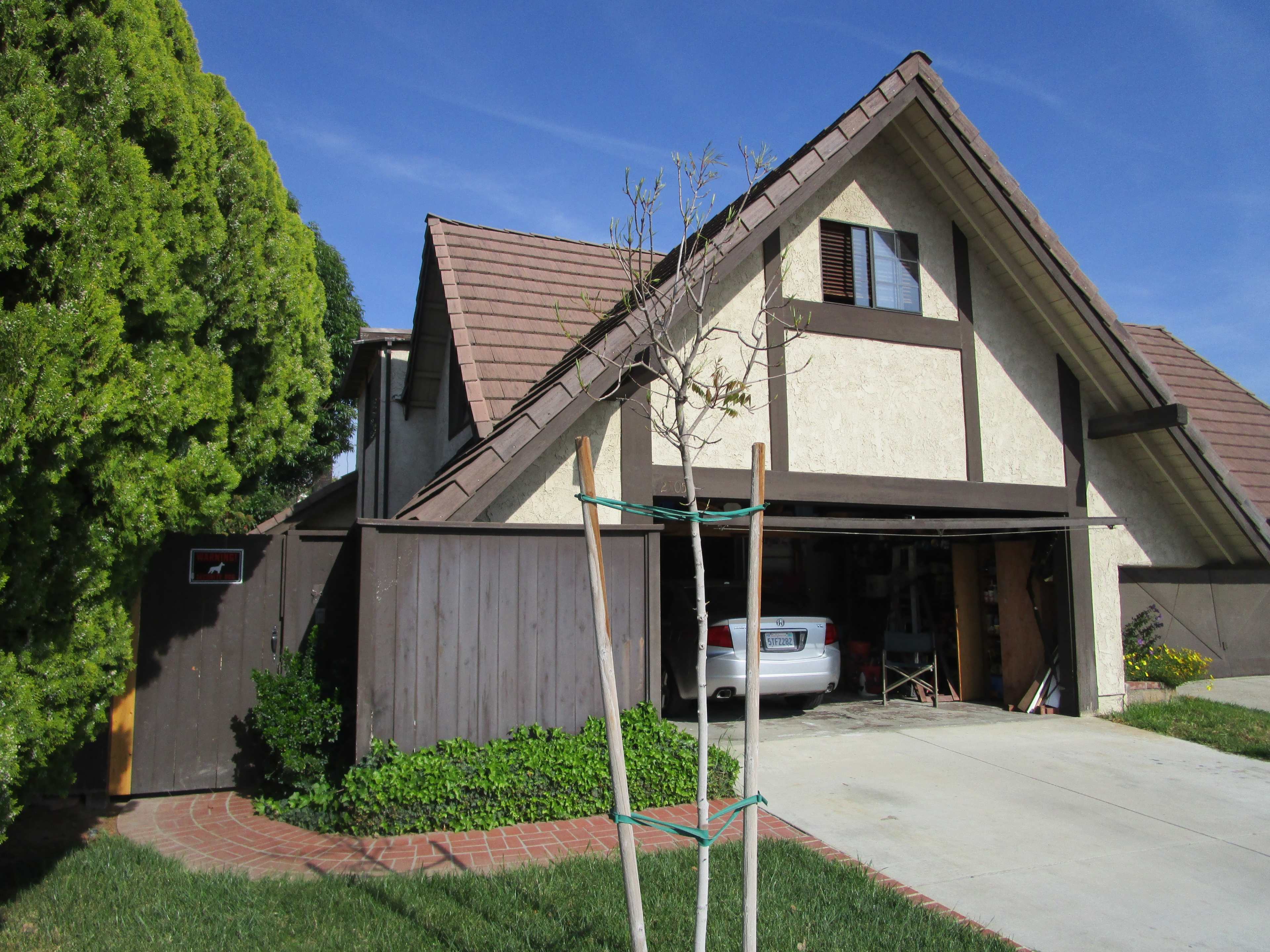 A two-story house with a steep gabled roof and a garage partially open on the right side.