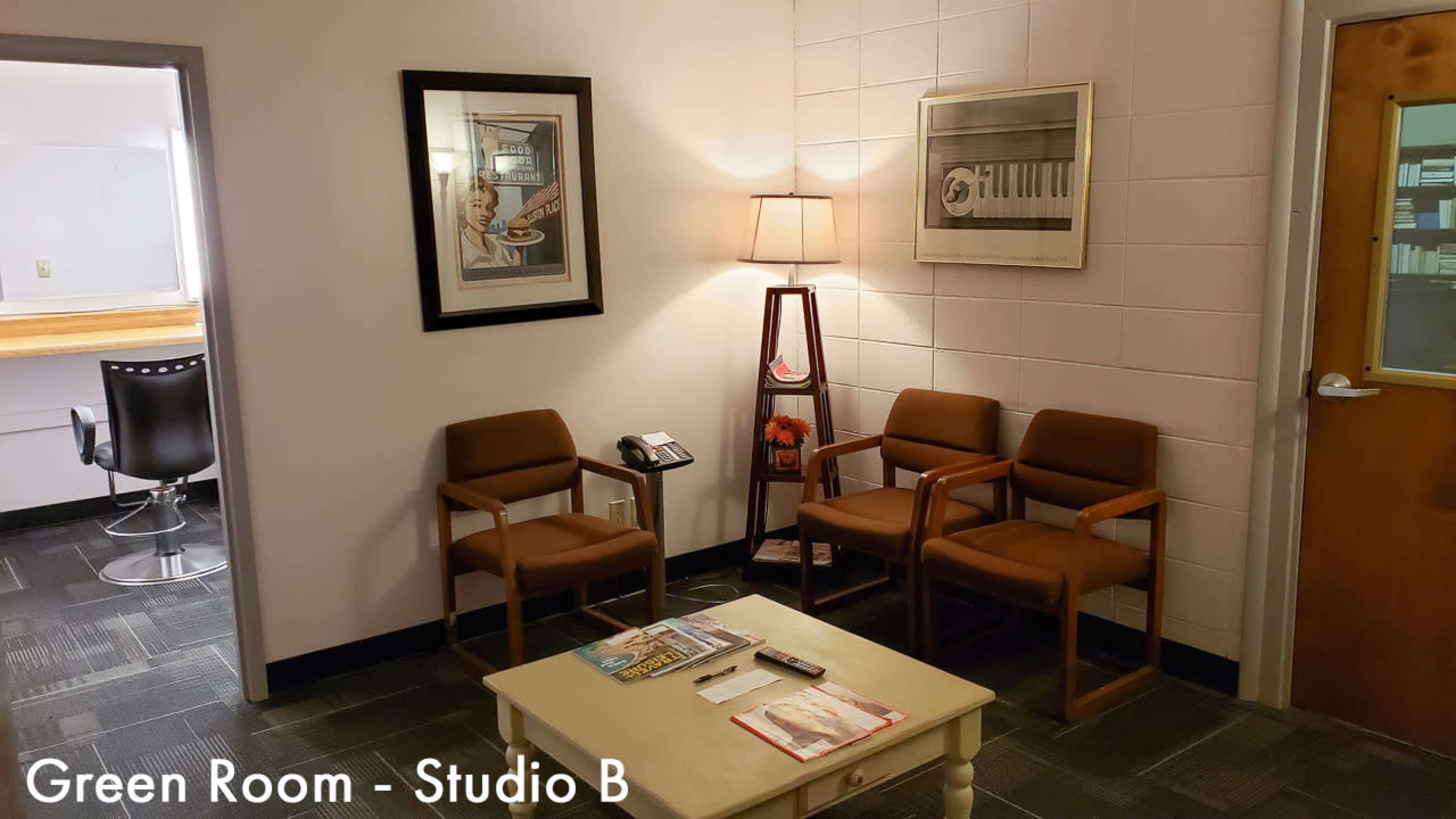 A small waiting area with three brown chairs, a lamp, a table with magazines, and a framed artwork on the wall.