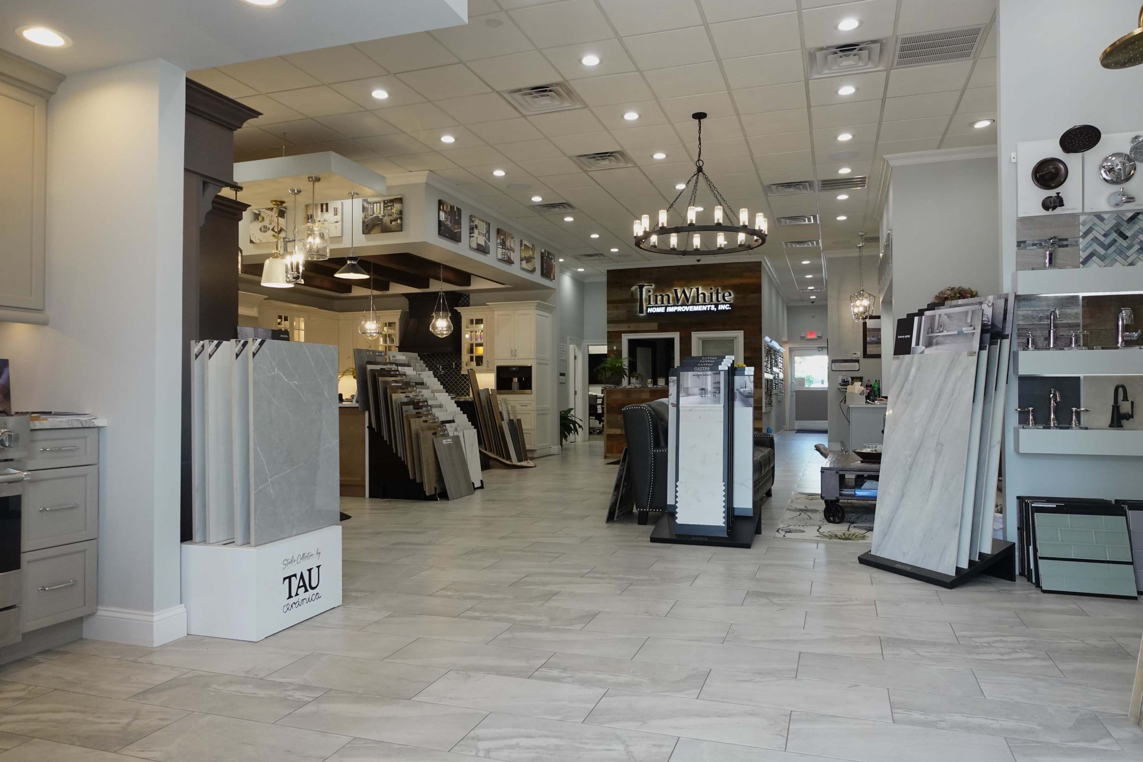 A spacious showroom featuring displays of various tile and flooring options, illuminated by bright overhead lighting.