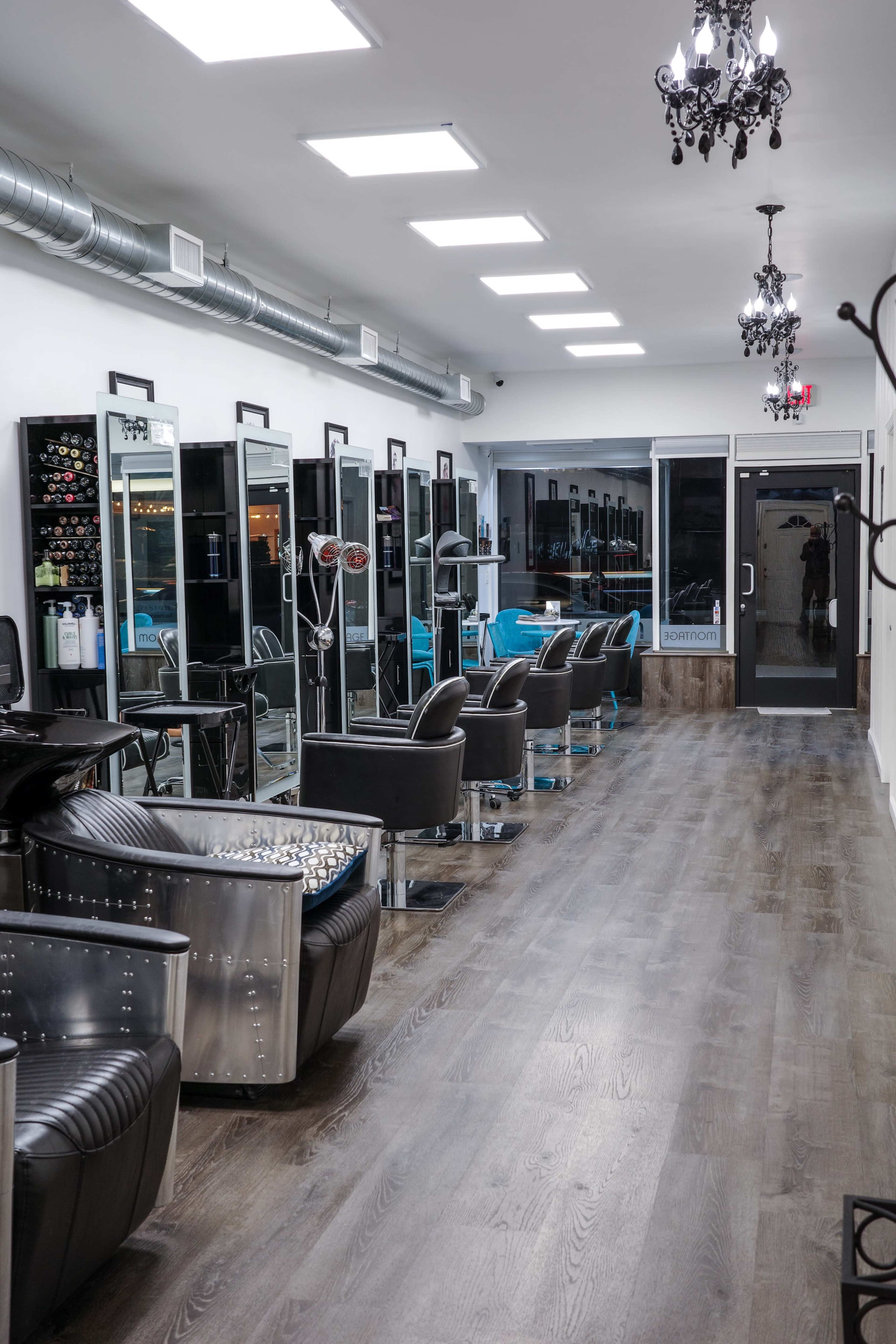 A modern hair salon with styling stations, mirrors, and black chairs arranged along a well-lit corridor.