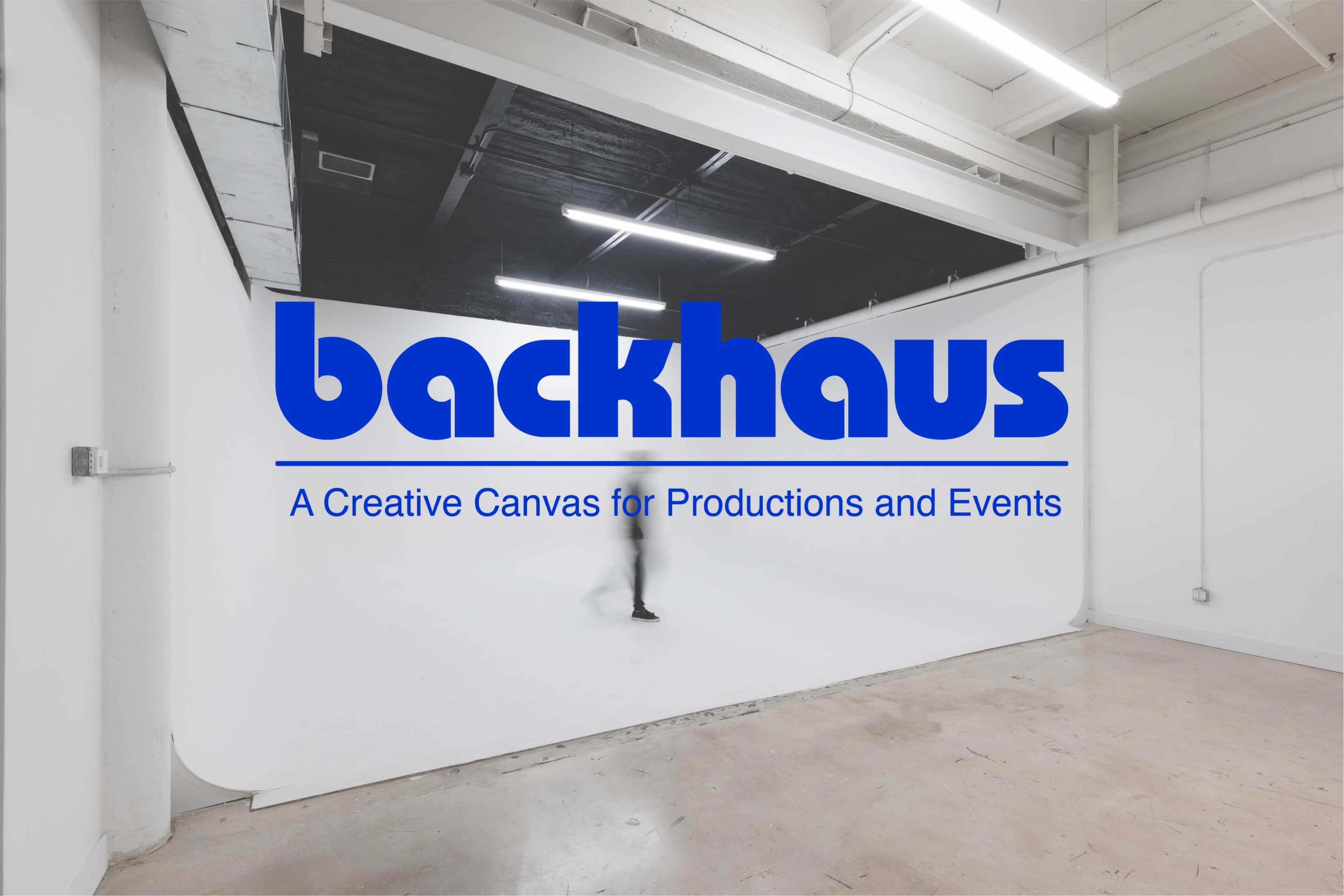 A spacious, well-lit studio with a white backdrop and a person walking in the center, featuring the text "backhaus" prominently displayed.