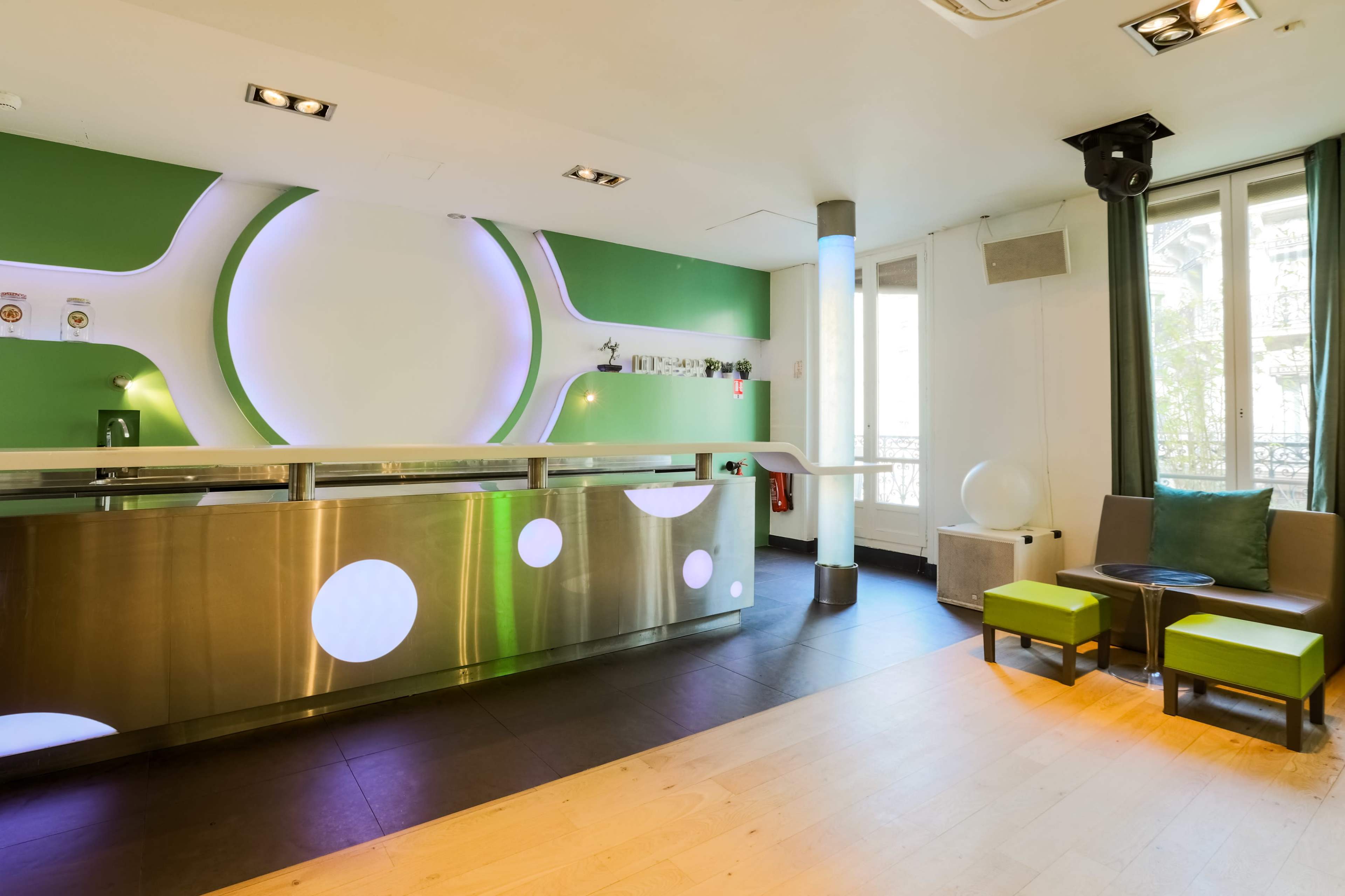 A modern, minimalist reception area with a metallic front desk and green accent walls.