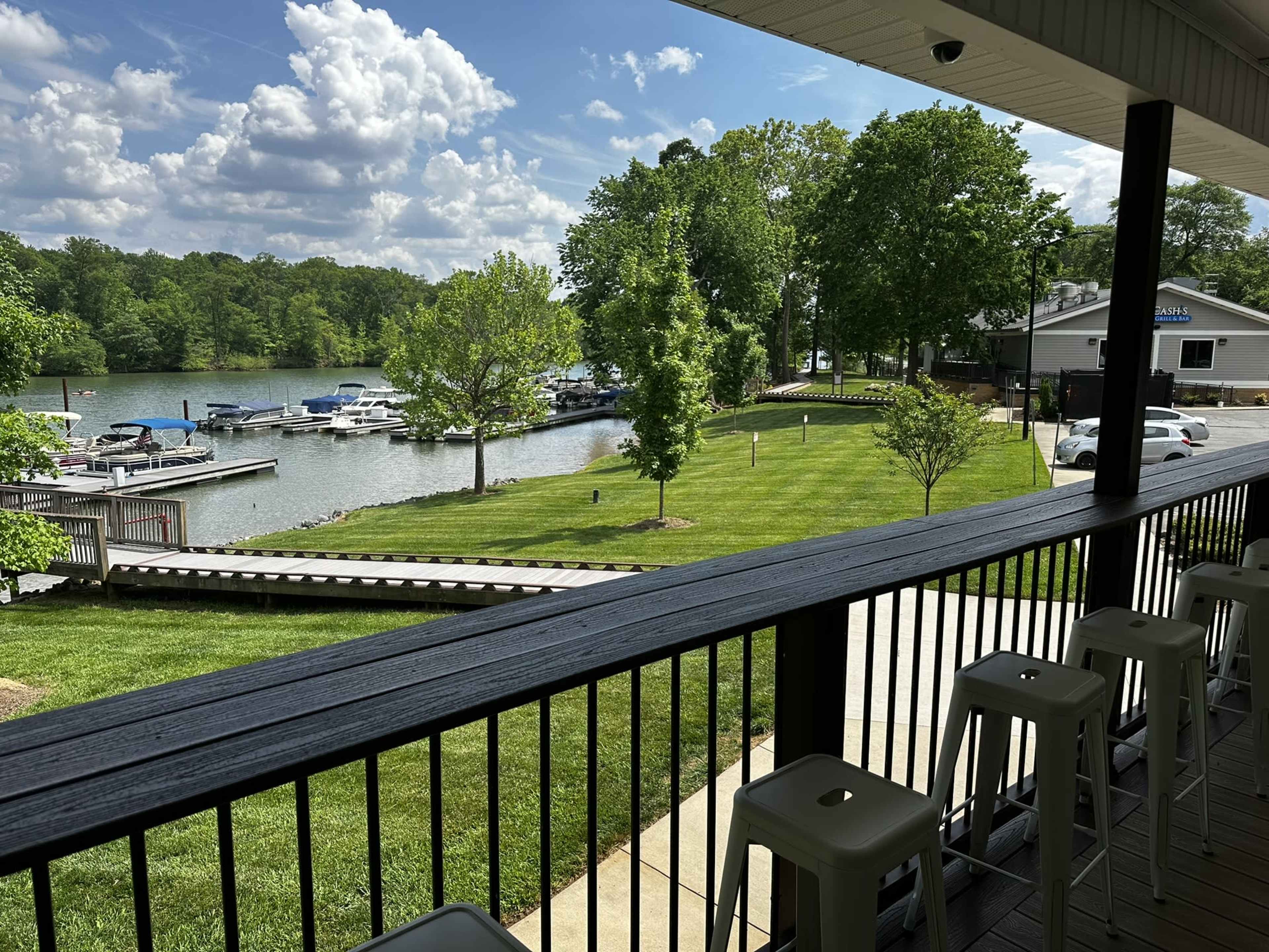 The image shows a view from a balcony overlooking a marina with several boats docked along a grassy shoreline and trees.