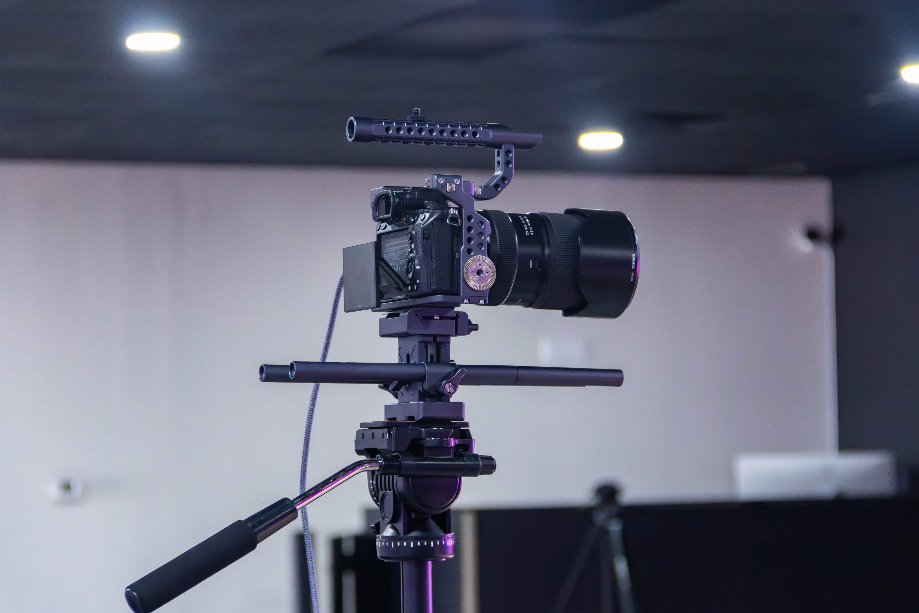 A camera mounted on a tripod is positioned in a studio setup with a blurred background.