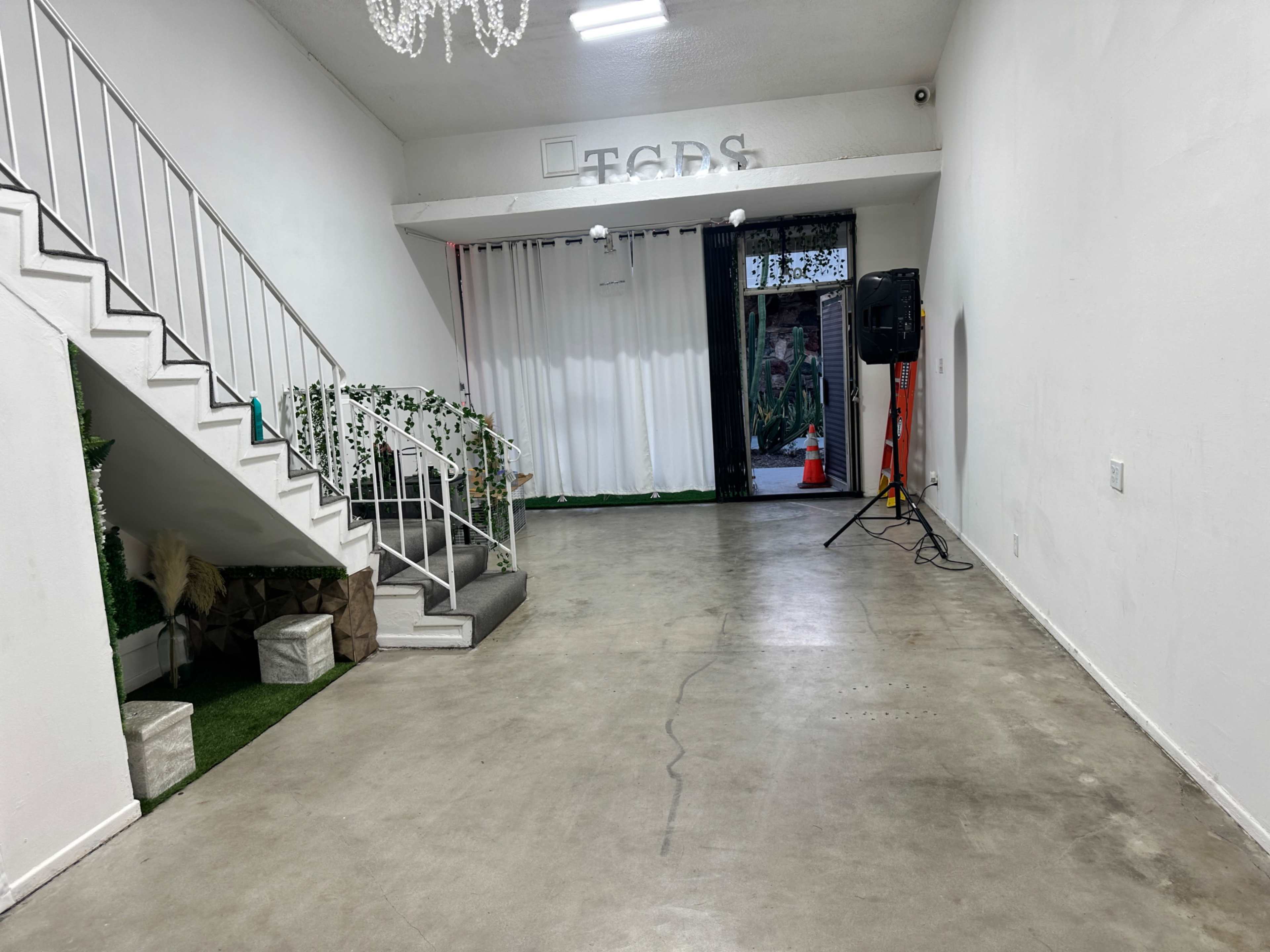 A spacious, empty room with a staircase on the left, a decorative curtain, and an entrance that opens to an outdoor area.