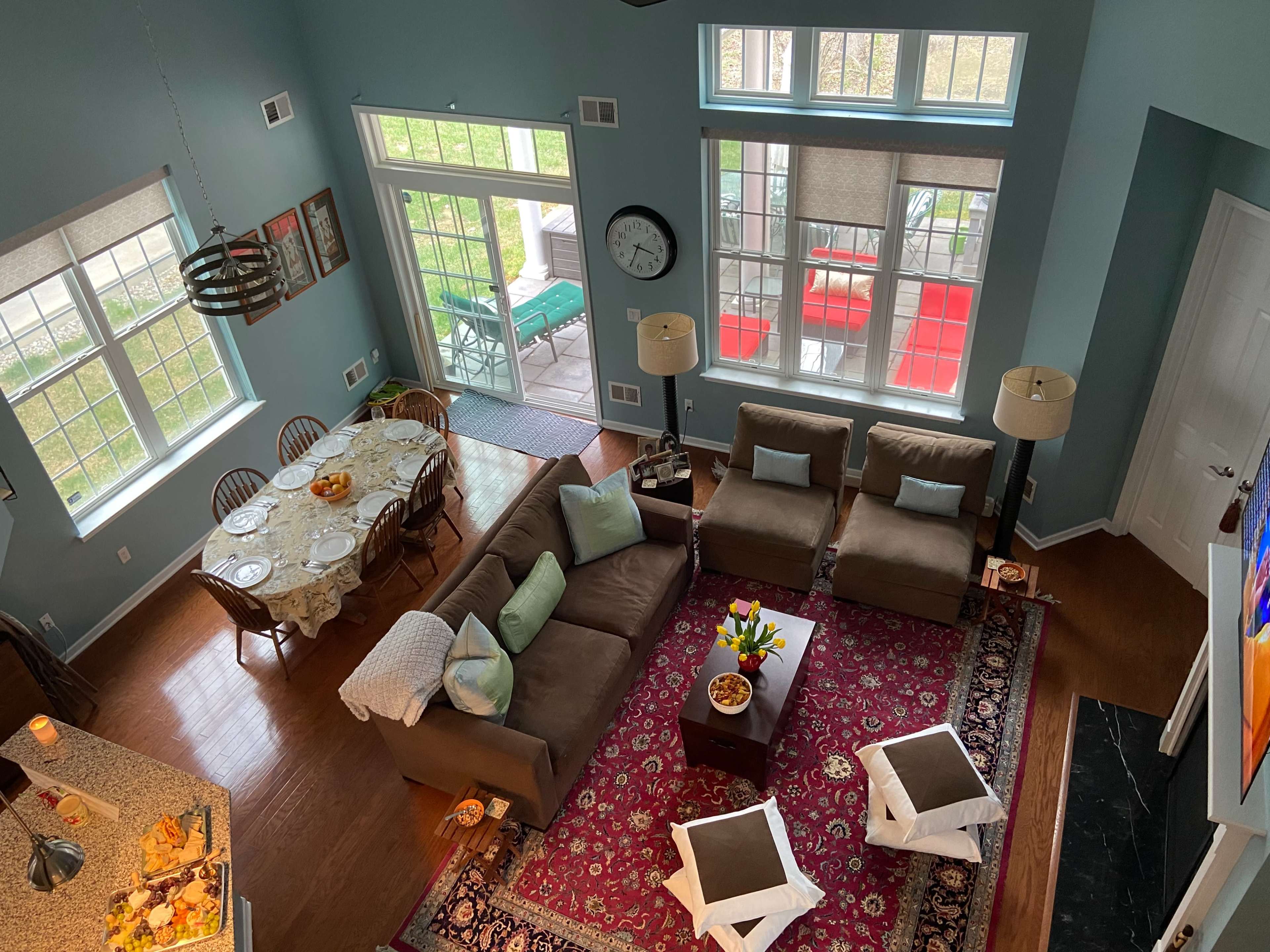 A spacious living area with a seating arrangement, dining table, and large windows, illuminated by natural light.