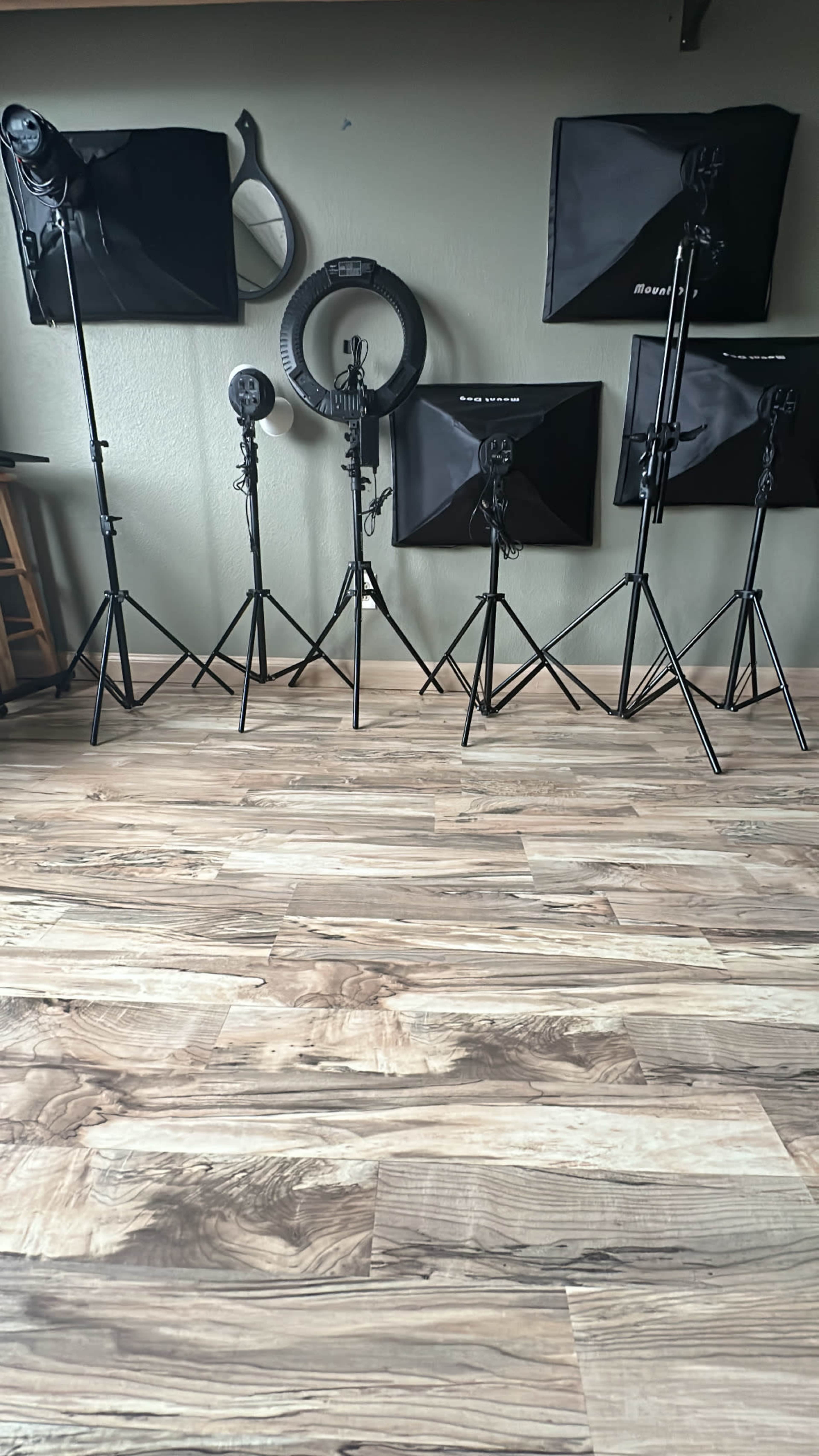 The image shows a well-organized studio space with multiple lighting stands and softboxes on a wooden floor.