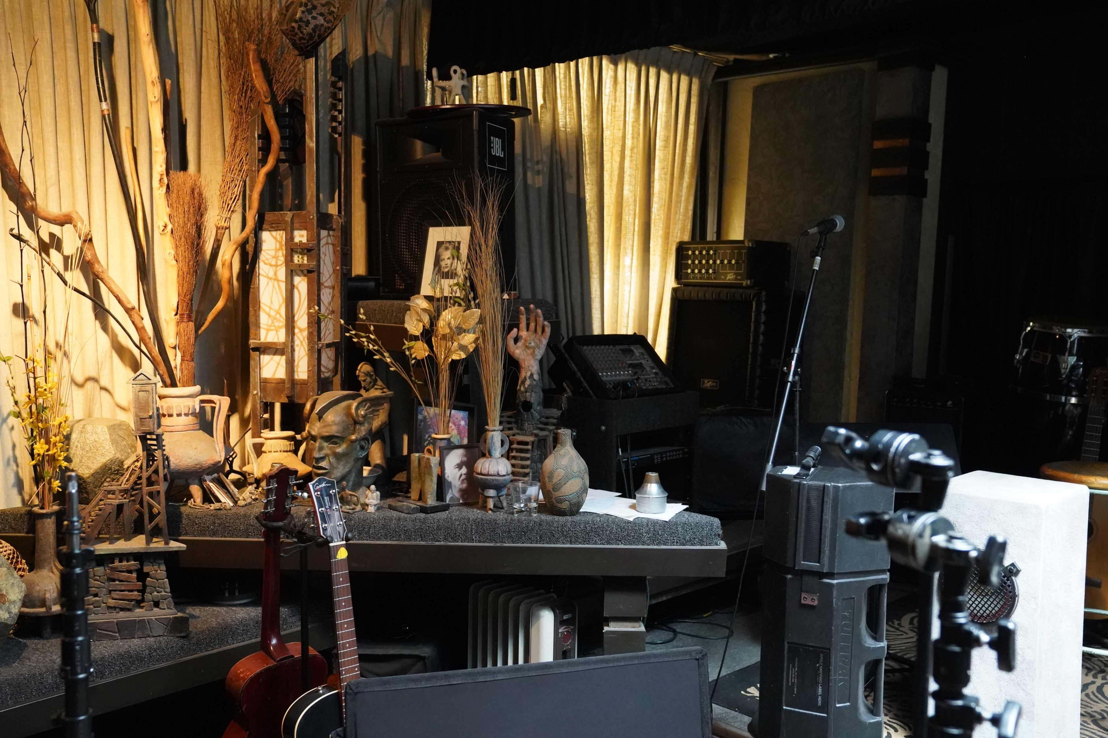 A stage setup with musical instruments, decorative elements, and audio equipment in a dimly lit room.