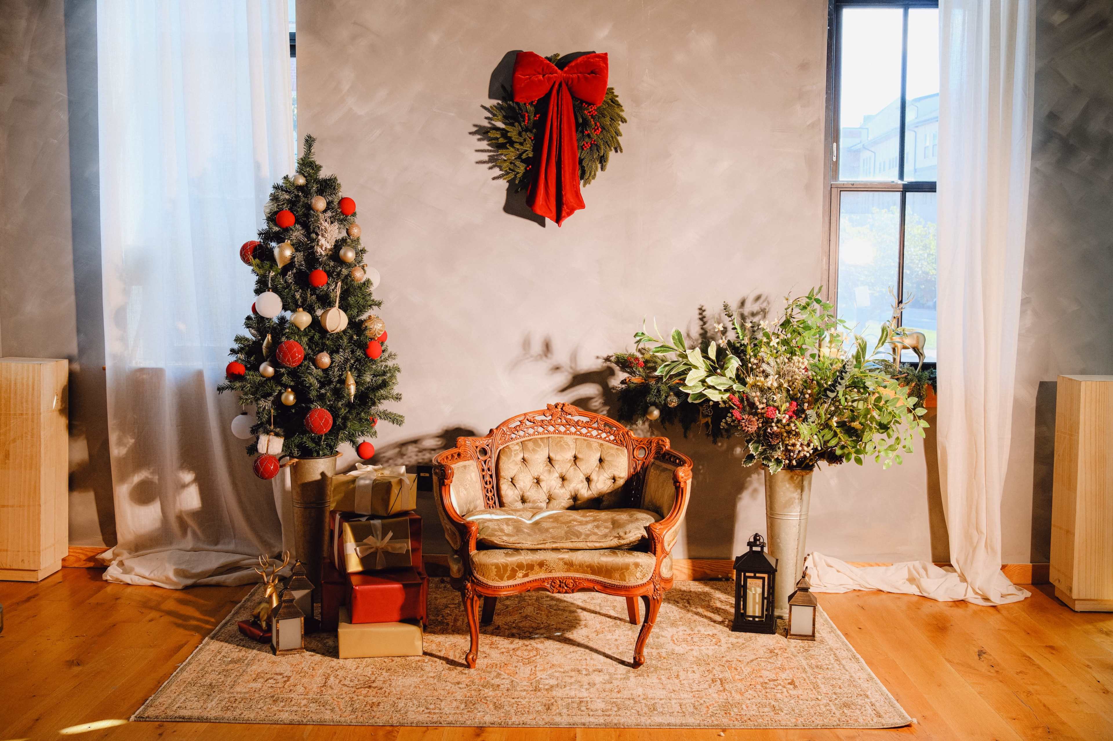 The scene features a decorated Christmas corner with a small tree, a vintage couch, festive greenery, and wrapped presents.