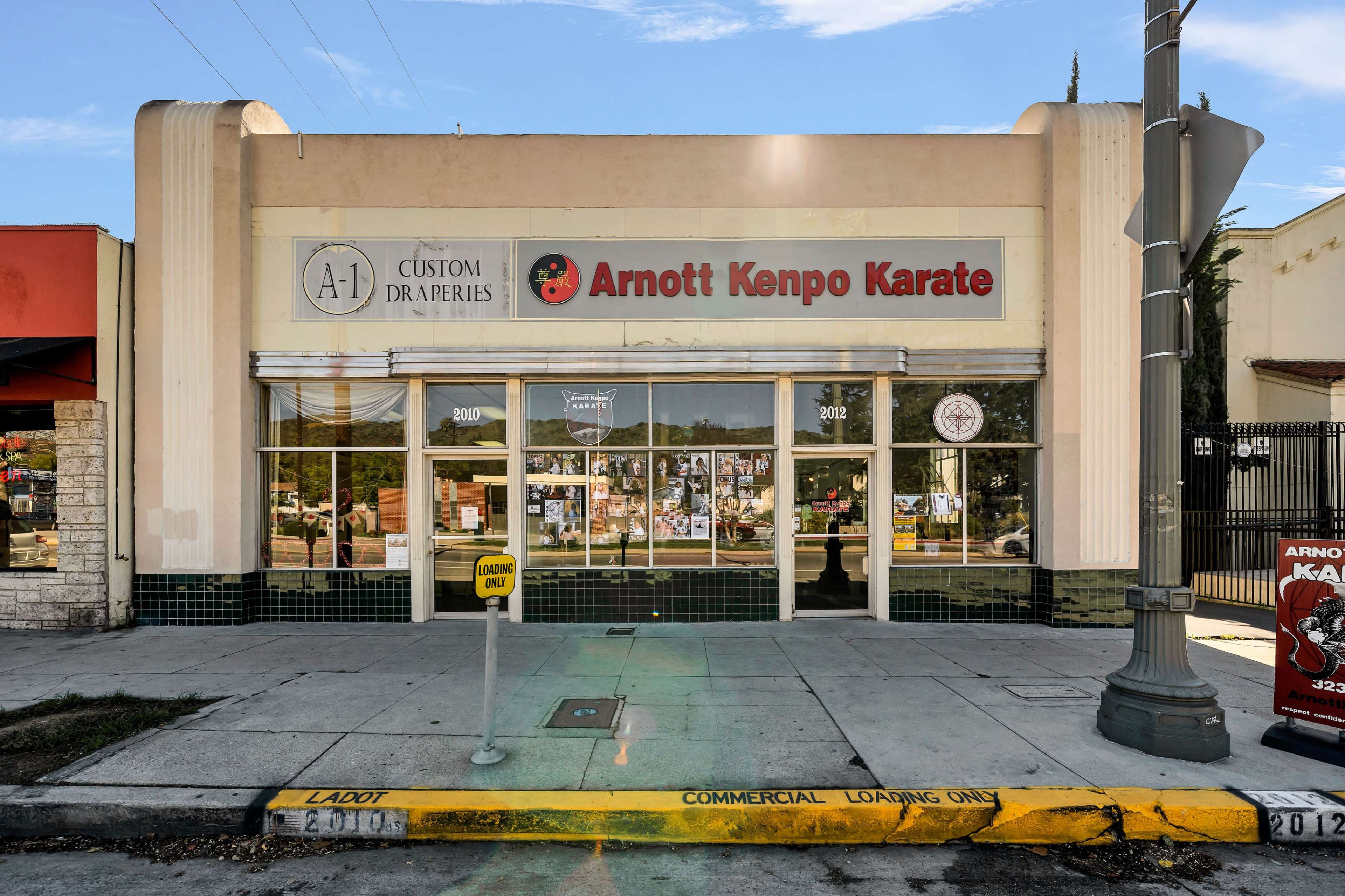 A storefront featuring "Arnott Kenpo Karate" with large windows and signage, located next to a drapery shop.