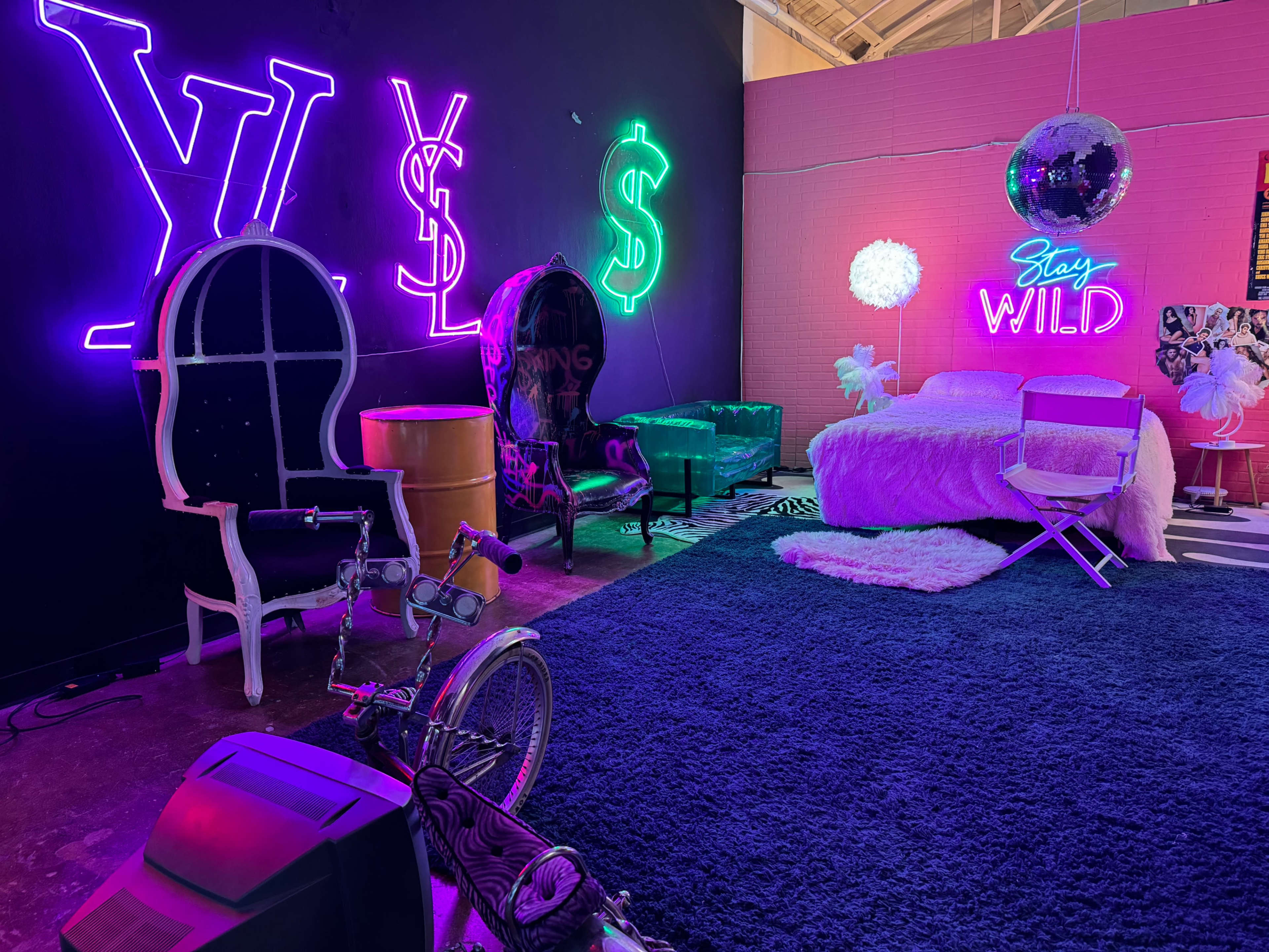 A vibrant interior space with neon signs, a mix of eclectic furniture, and a striking color palette.