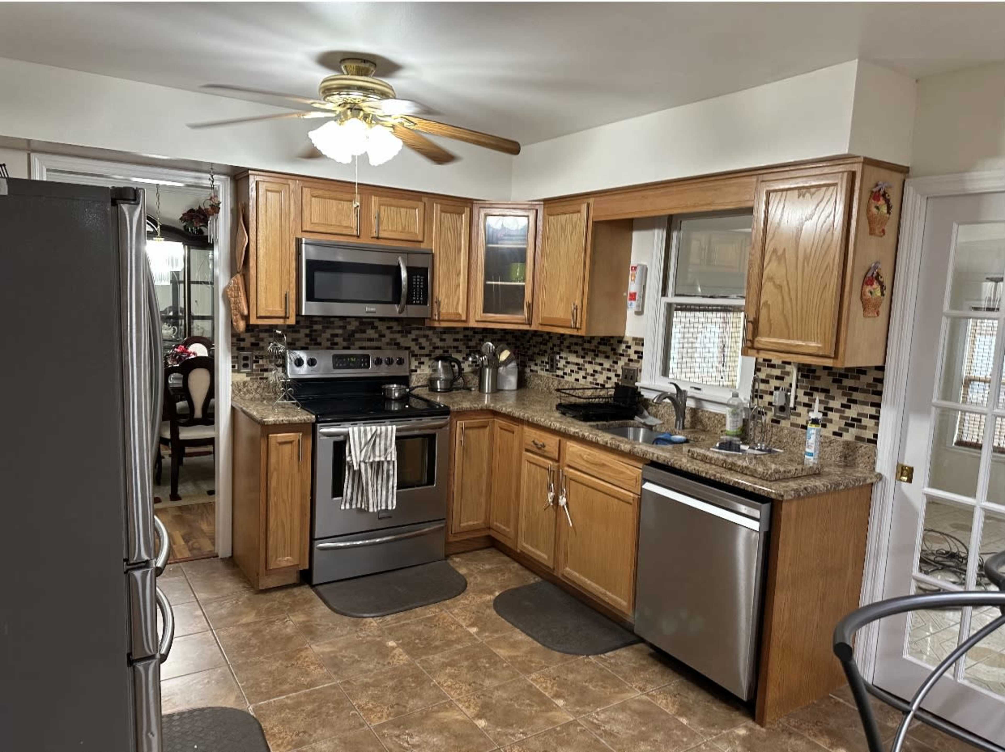 A kitchen with oak cabinets, stainless steel appliances, and a tiled floor.
