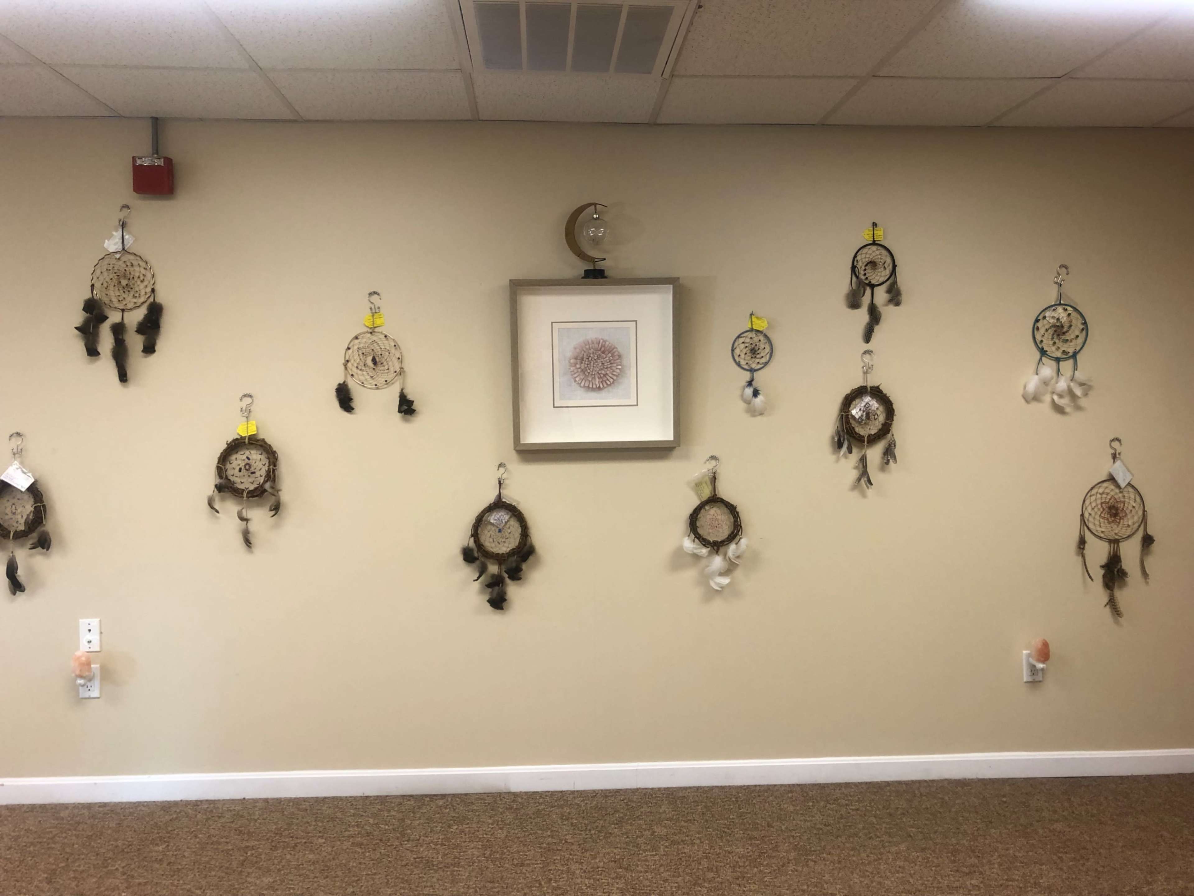 A wall decorated with several dreamcatchers and a framed artwork in the center.