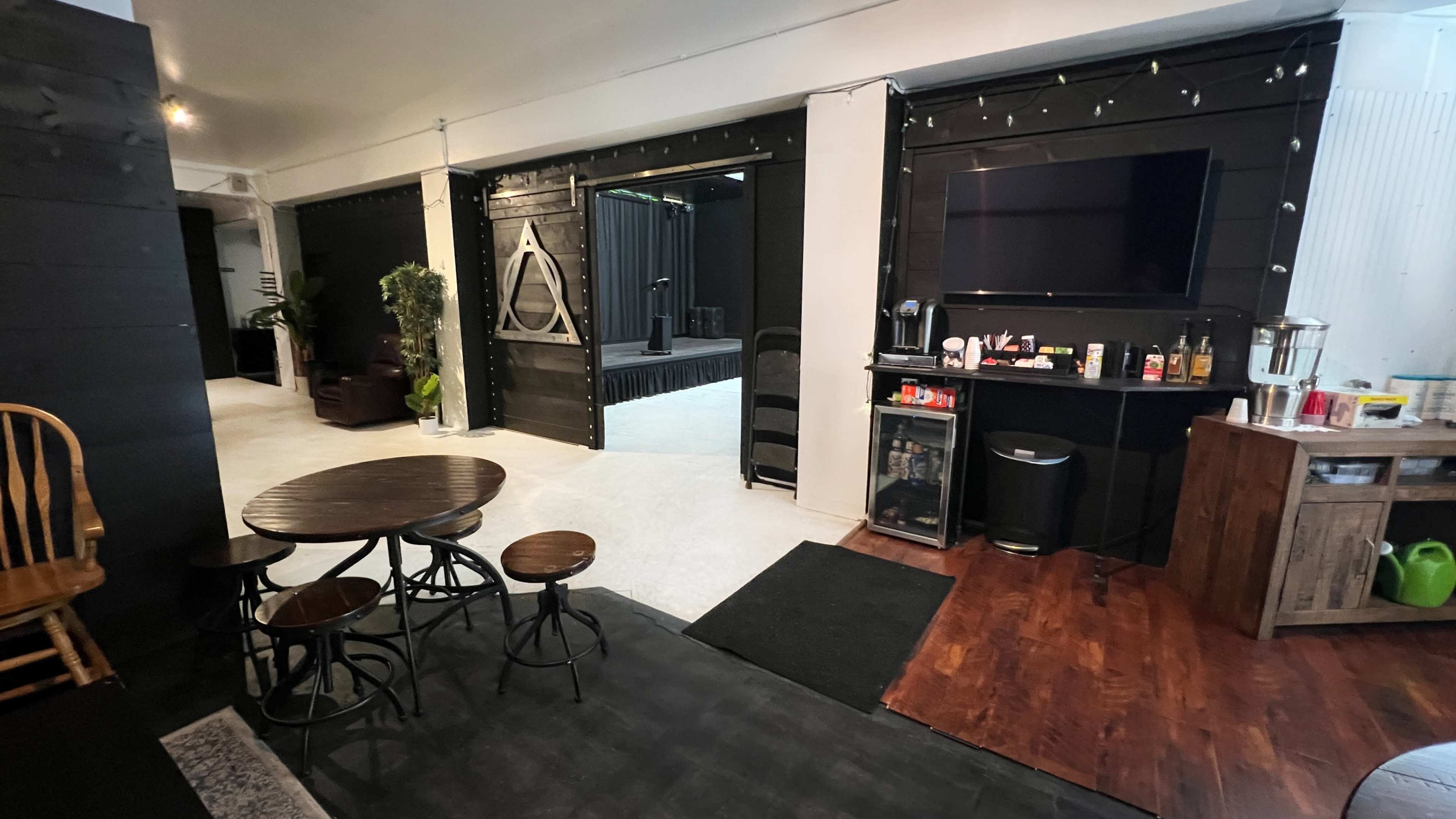 A modern, open interior space with a snack area, seating, and a stage behind a sliding door.