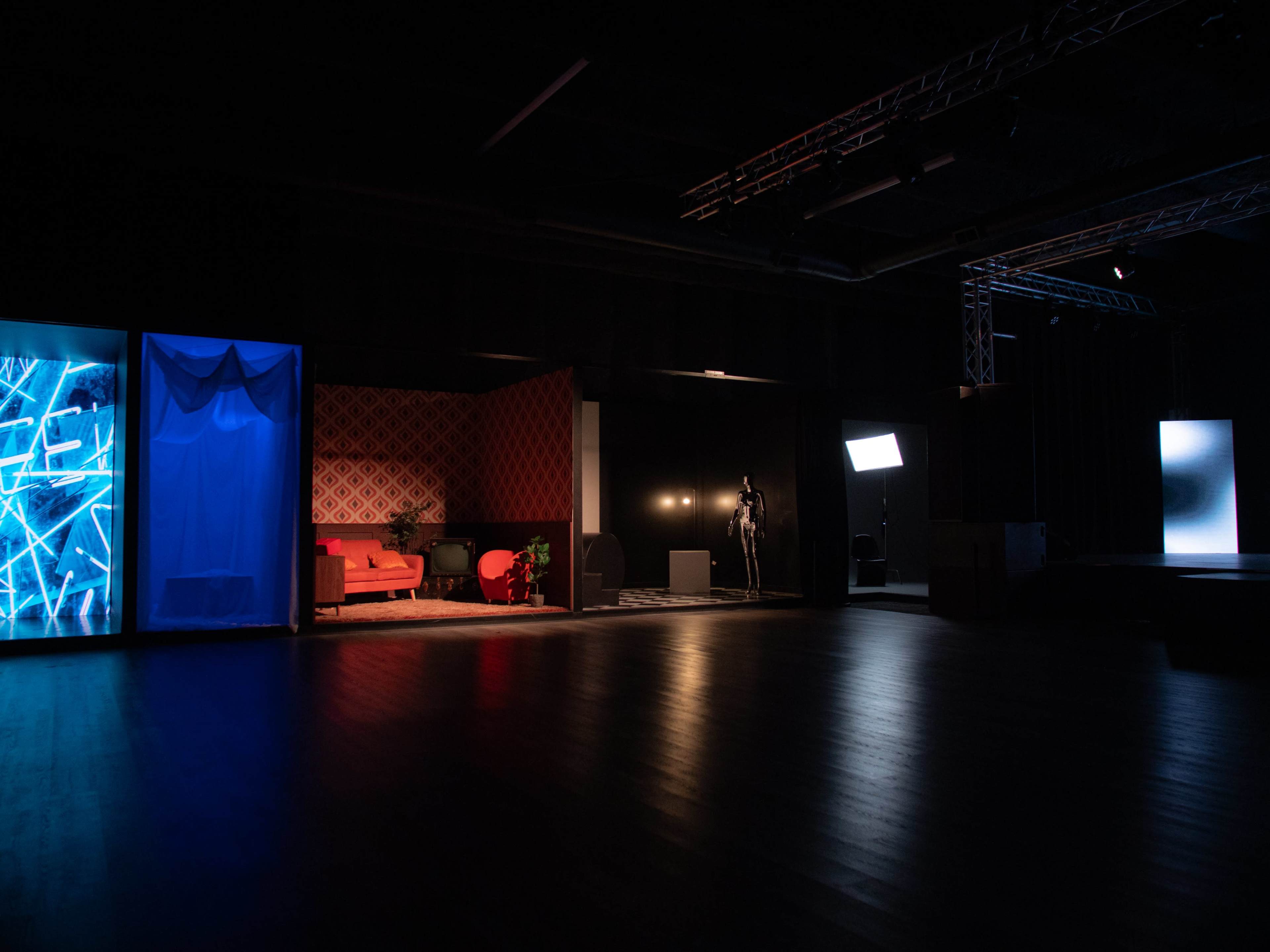 The scene shows an art space featuring various installations, including a red sofa, abstract lighting, and a mannequin against a dark backdrop.