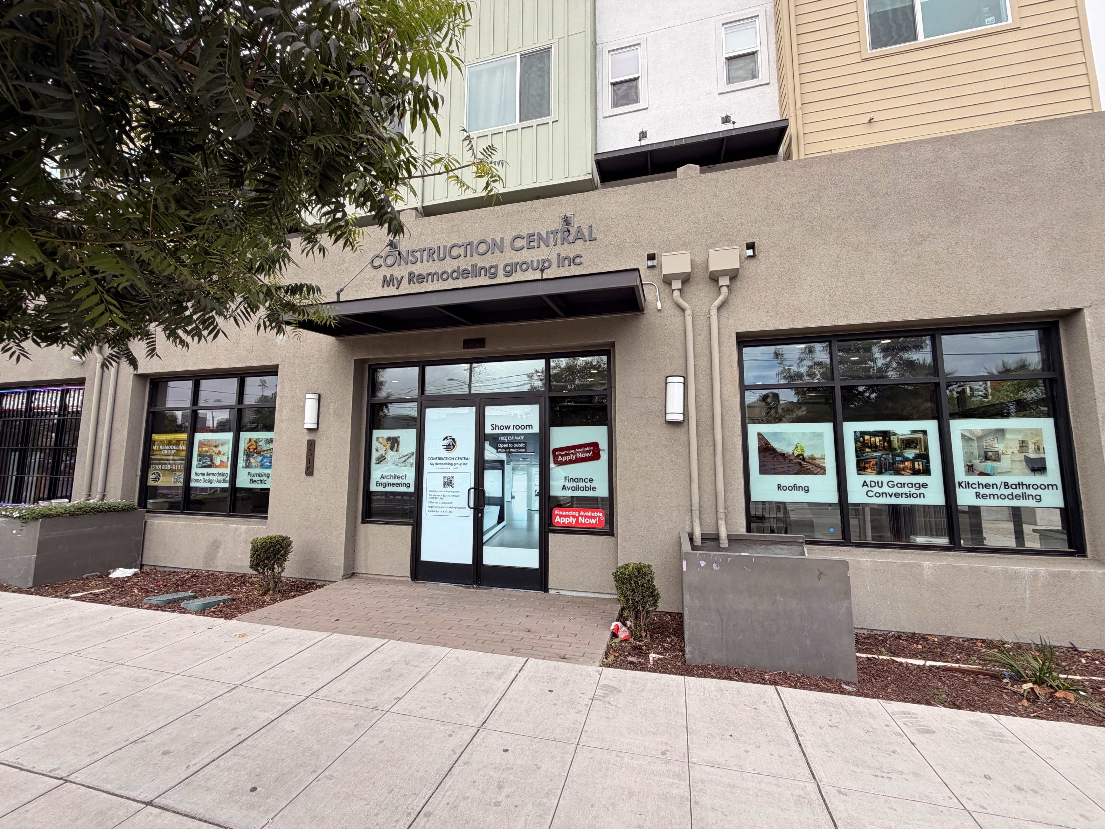 The image shows the exterior of a business named "Construction Central," featuring large windows with promotional signs related to remodeling services.