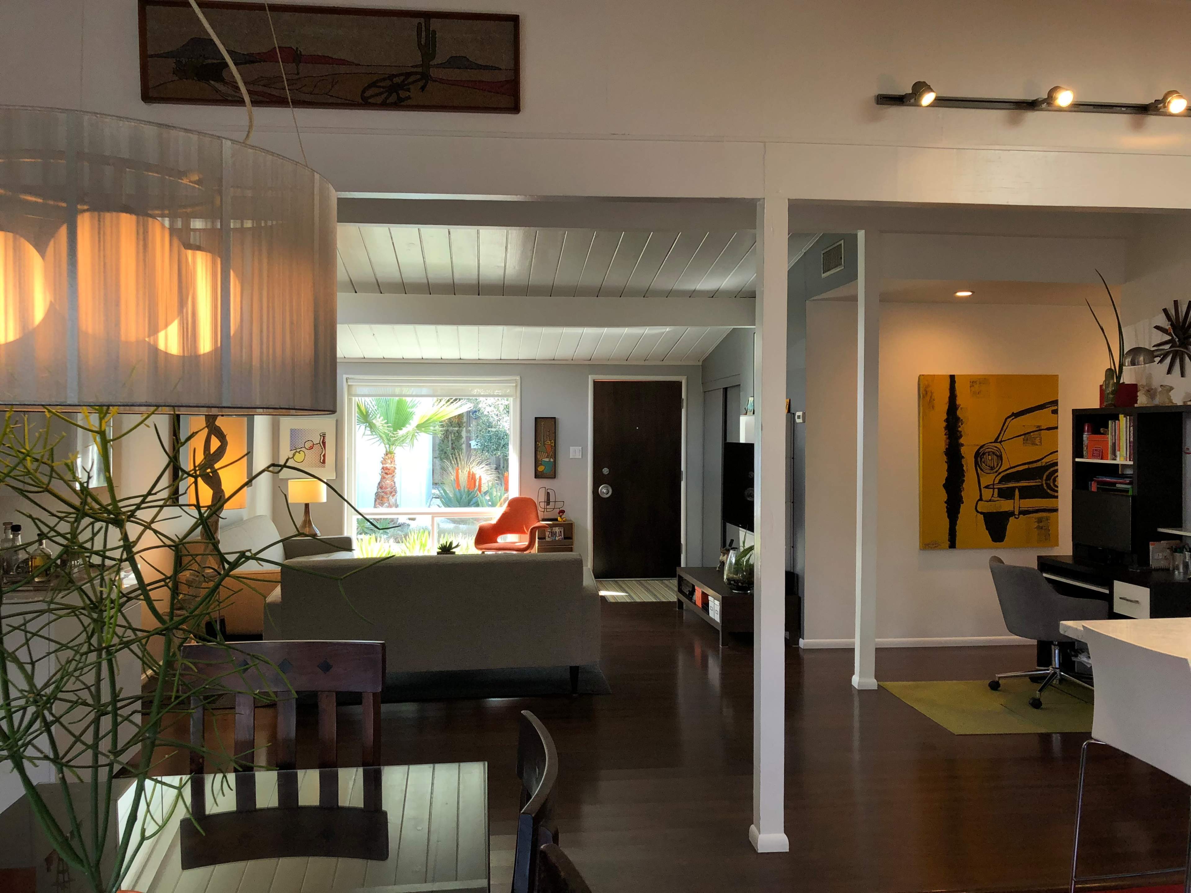 A spacious interior of a modern home with a living area visible in the foreground and a workspace area in the background.
