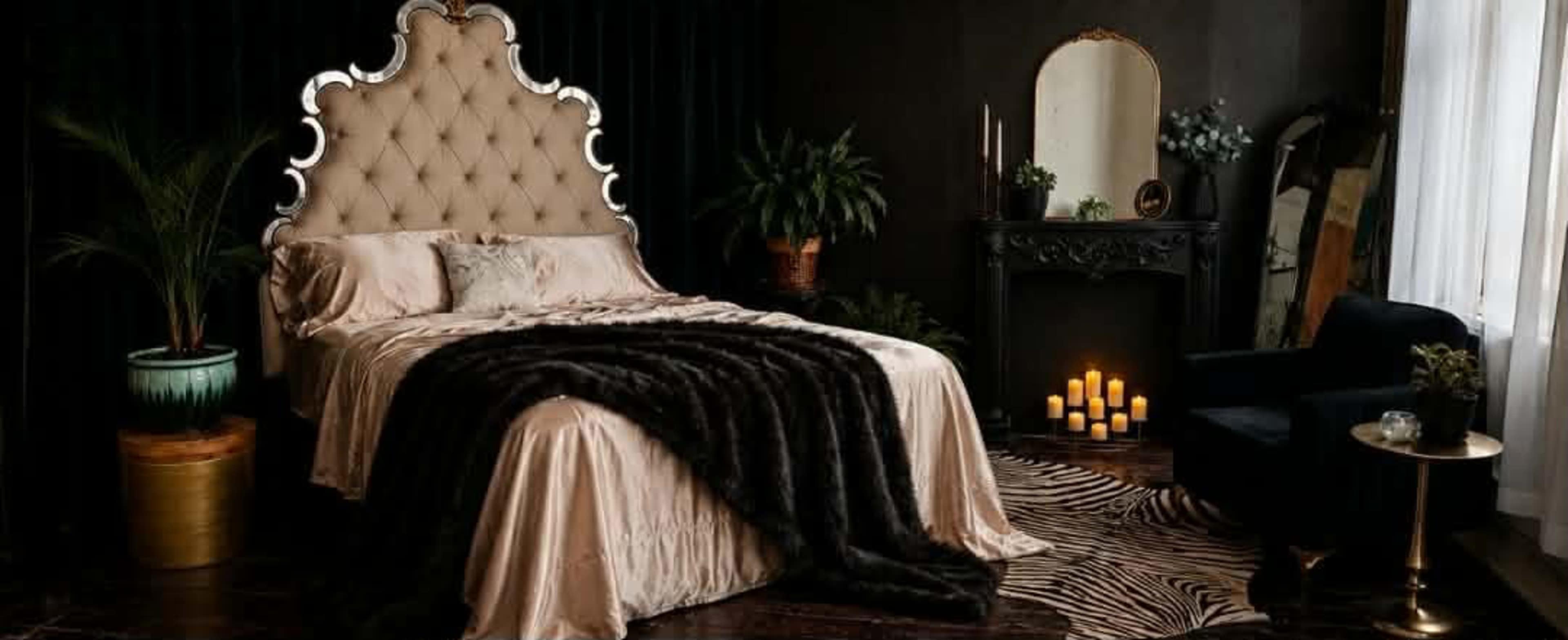 The image depicts a luxurious bedroom featuring a large tufted bed with a sleek headboard, a plush throw, decorative plants, and soft lighting from candles arranged on the floor.