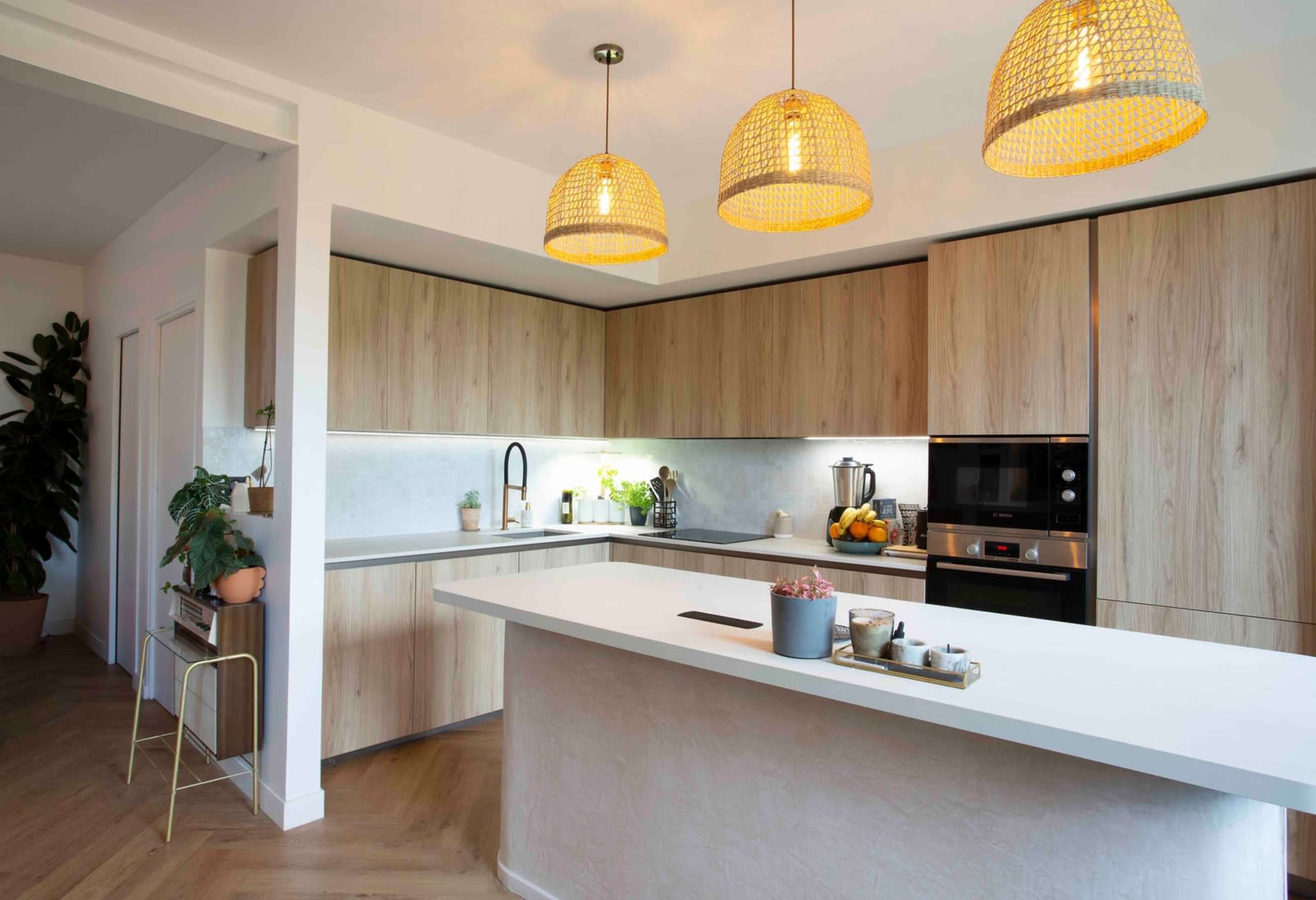 The kitchen features wooden cabinetry, a central island with a white countertop, and three pendant lights hanging above.