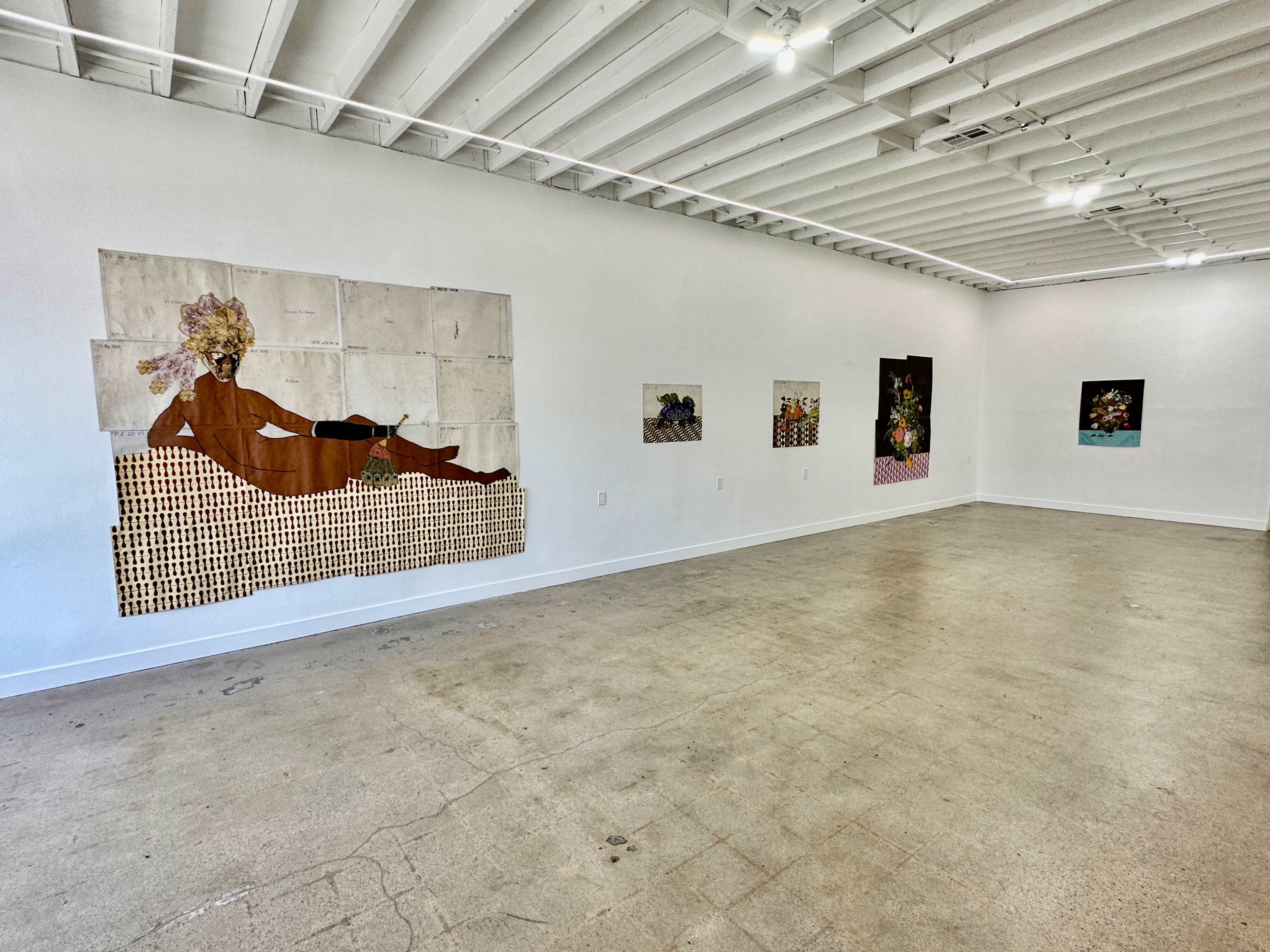 An art gallery with several artworks displayed on white walls and a concrete floor.