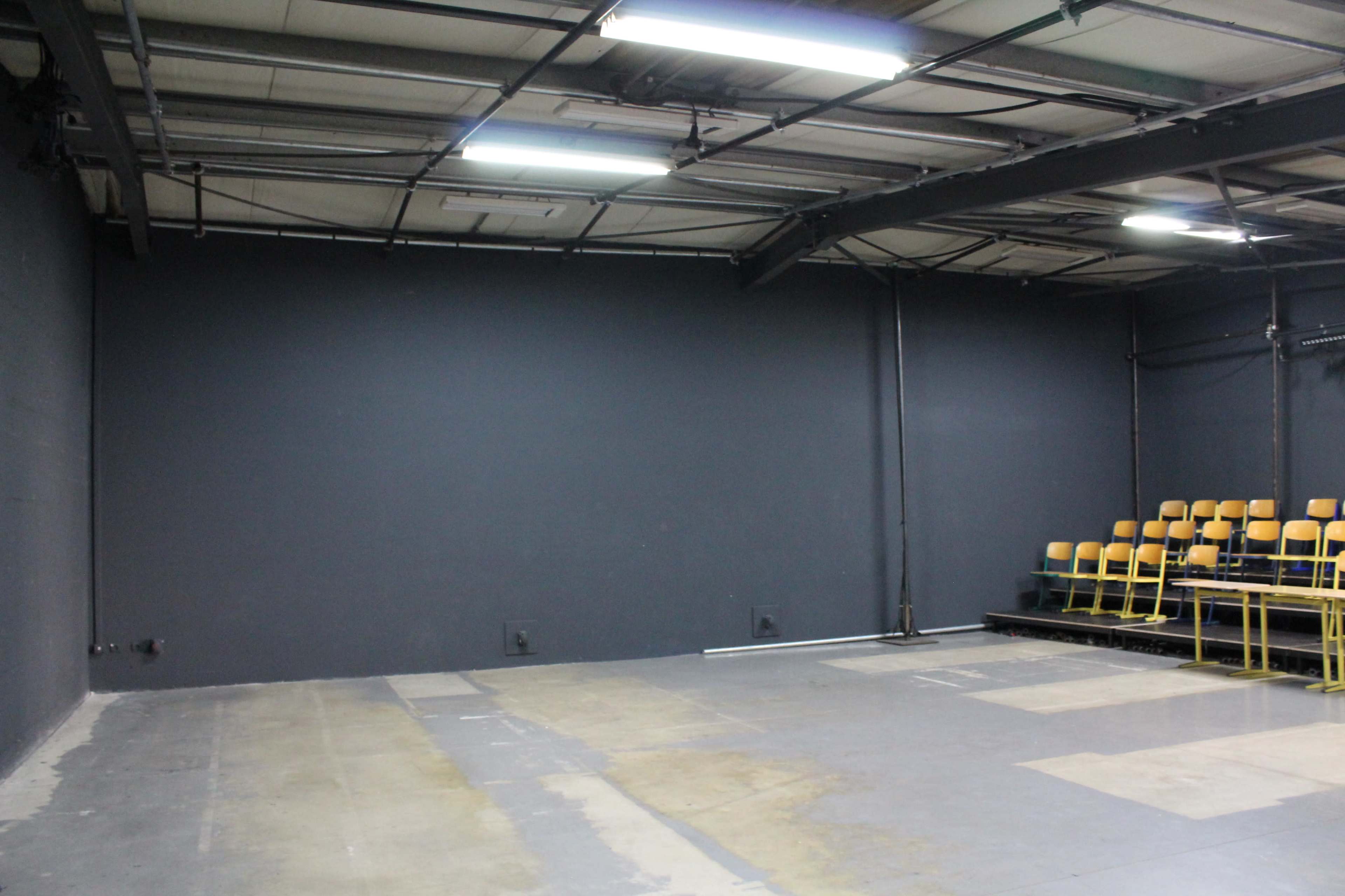 An empty indoor space with a gray wall and a row of yellow chairs against one side.