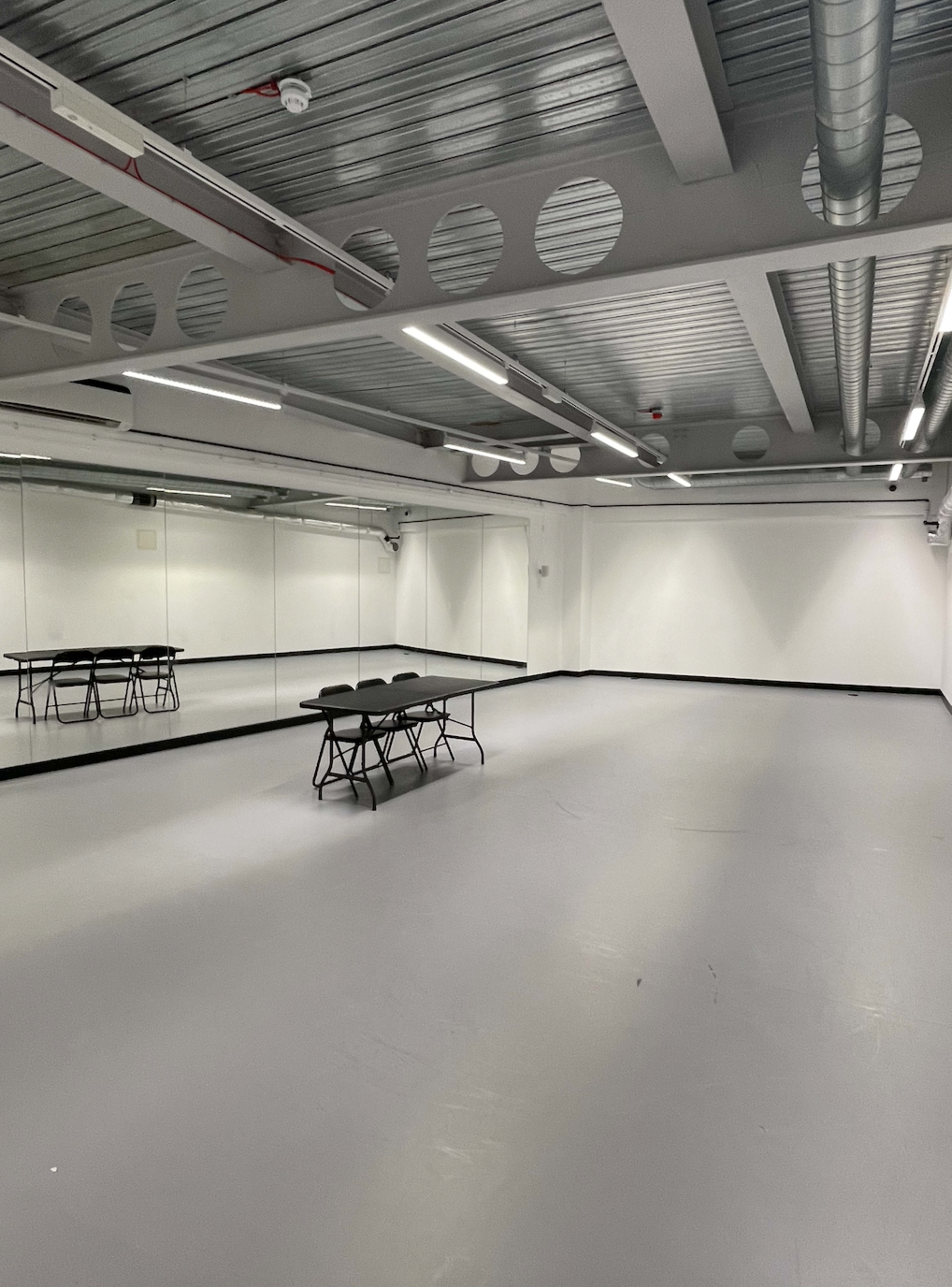 An empty dance studio with a mirrored wall and a table in the center.