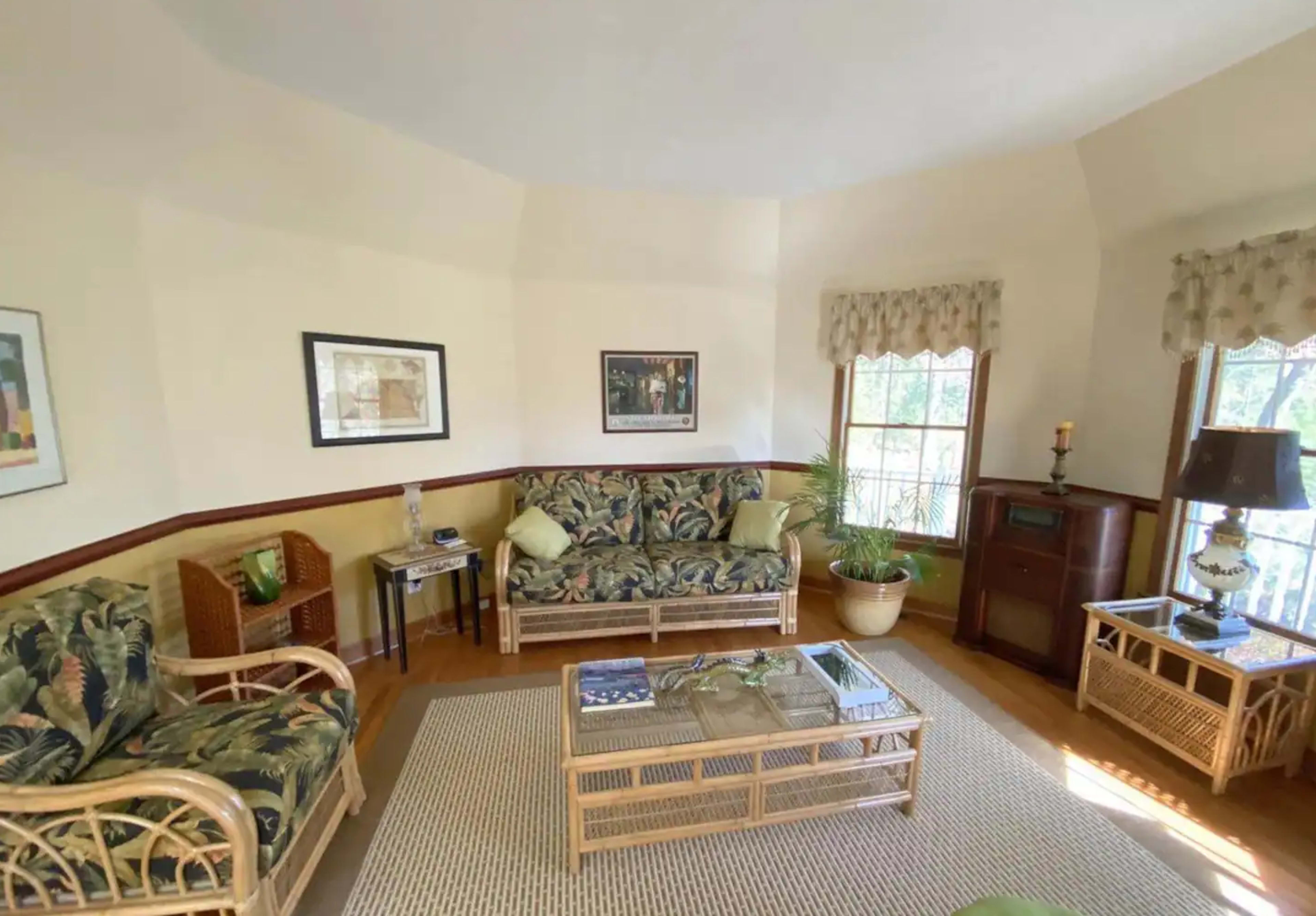 A living room with two floral-patterned sofas, a coffee table, and a window with light curtains.