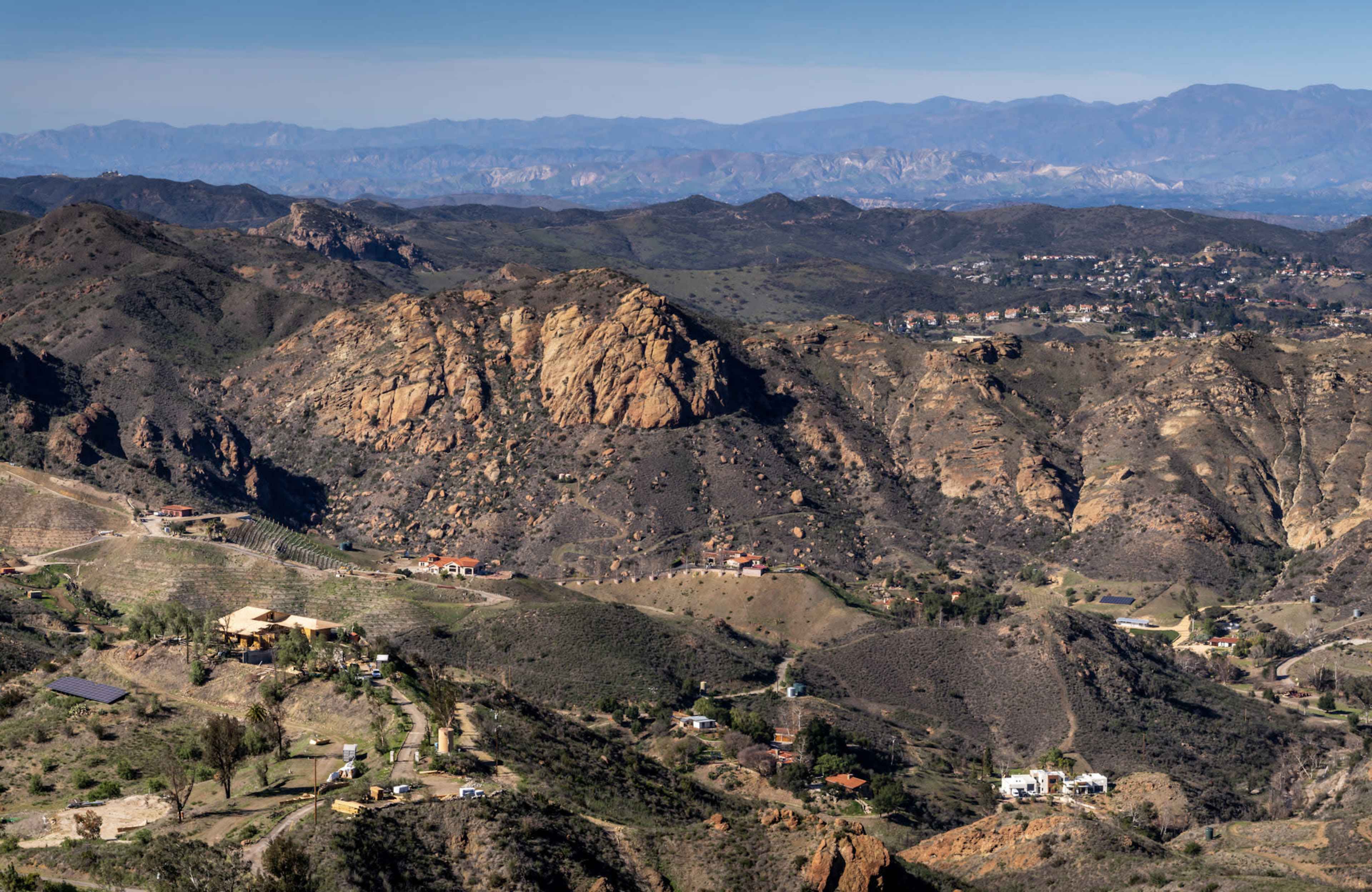 The image shows a mountainous landscape with rocky formations and scattered homes in the valleys below.