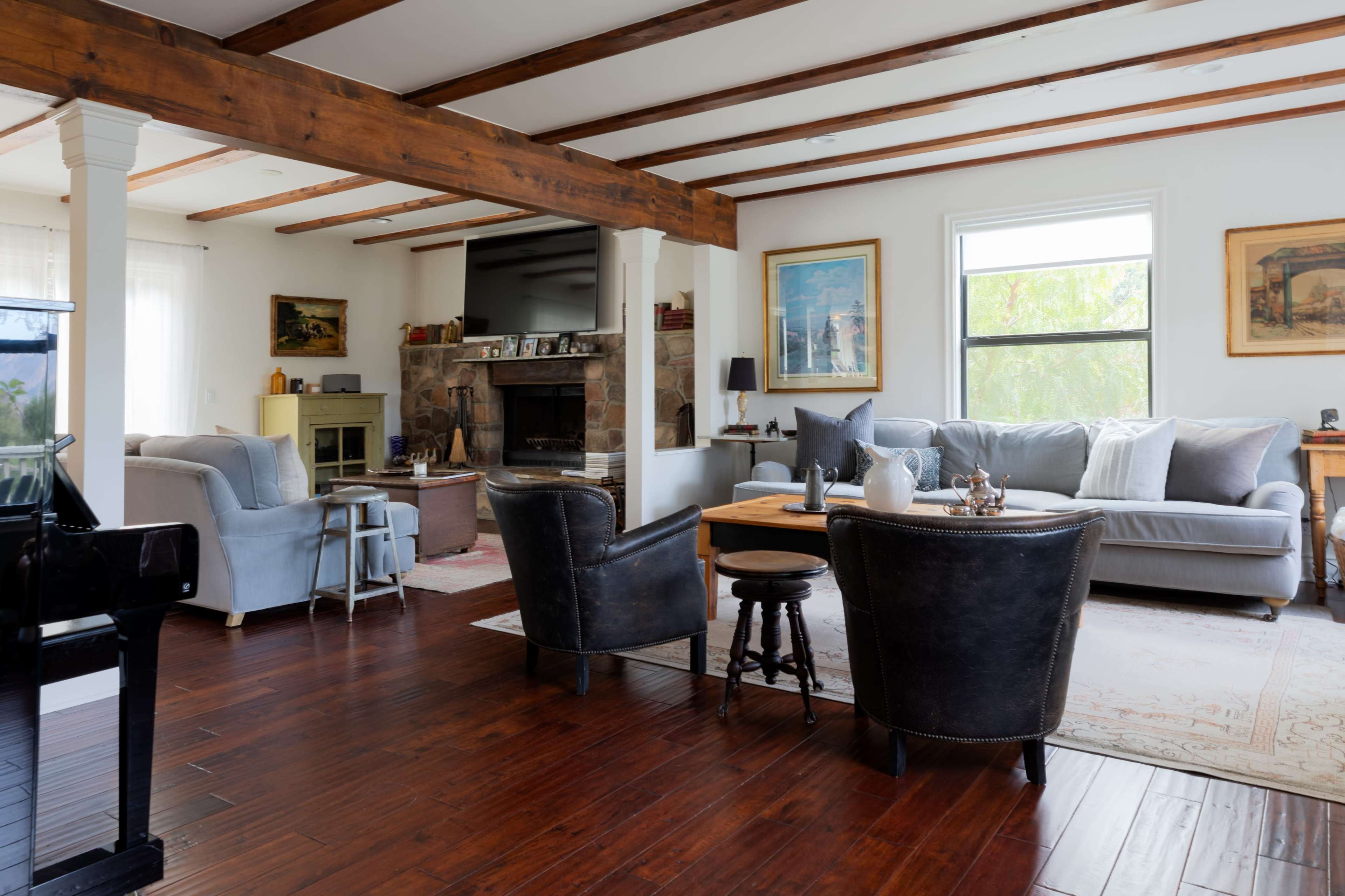 A comfortable living room features a mix of seating options, a fireplace, and wooden beams across the ceiling.
