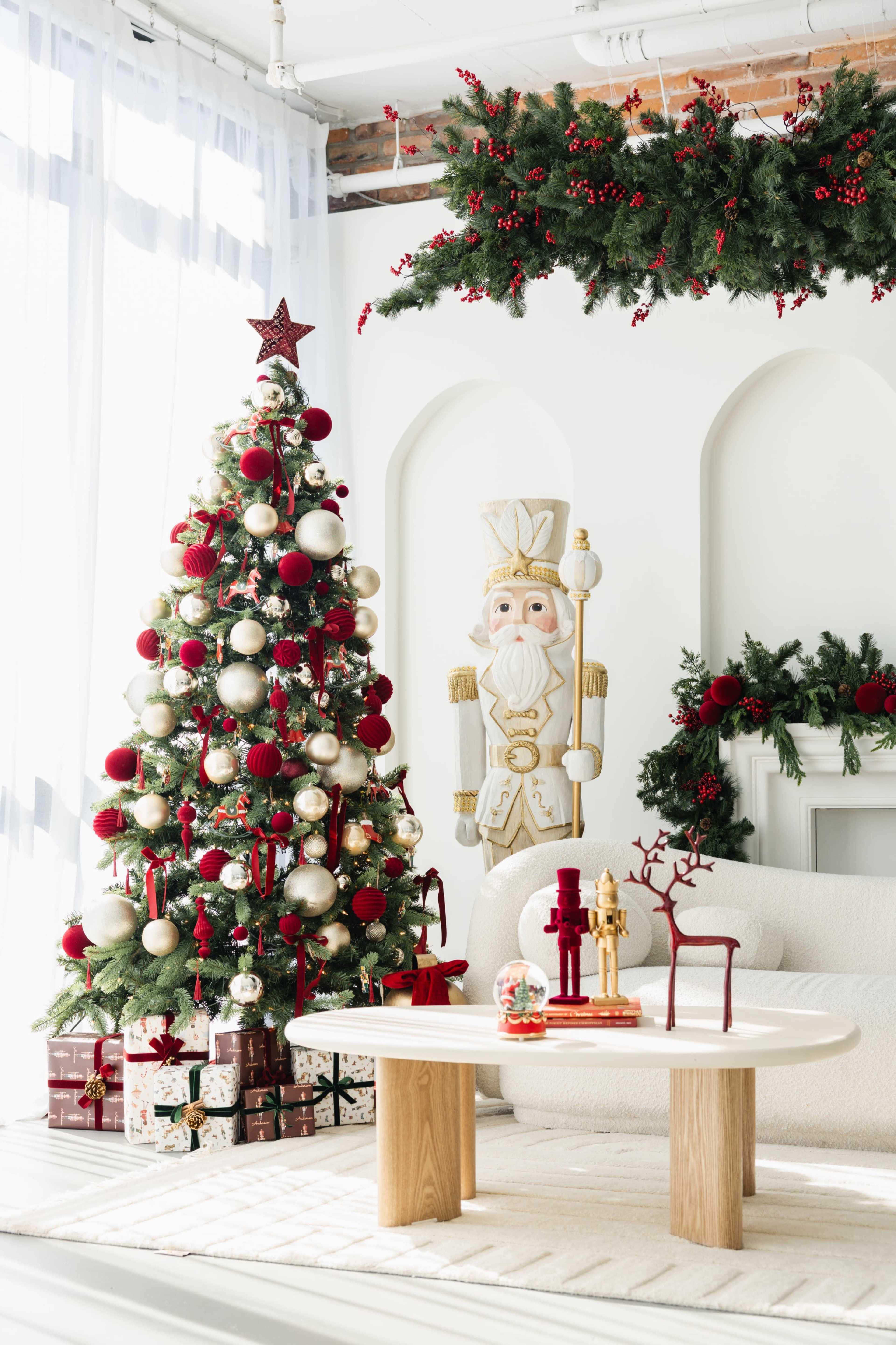 The image features a brightly decorated Christmas tree with red and gold ornaments beside a nutcracker figure, complemented by holiday decorations on the wall and a cozy seating area.